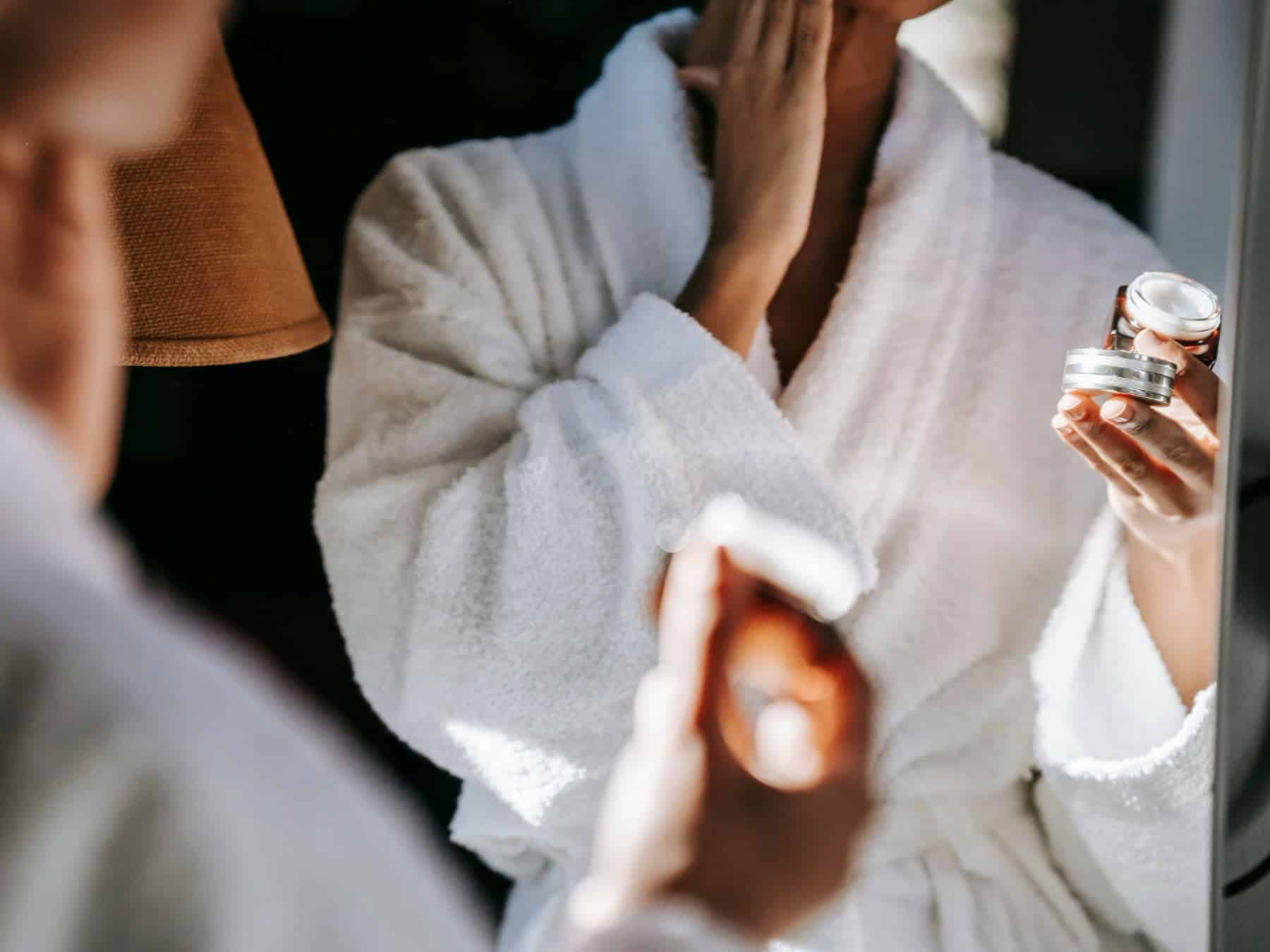 Woman putting on skin care in her bathroom in homes of getting rid of hormonal acne naturally.
