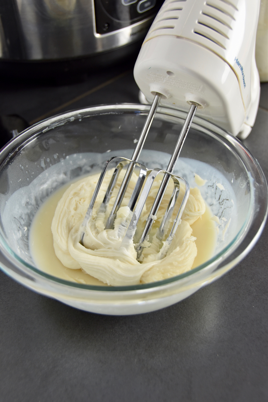 Whipping the body butter with a handheld mixer and adding body butter.