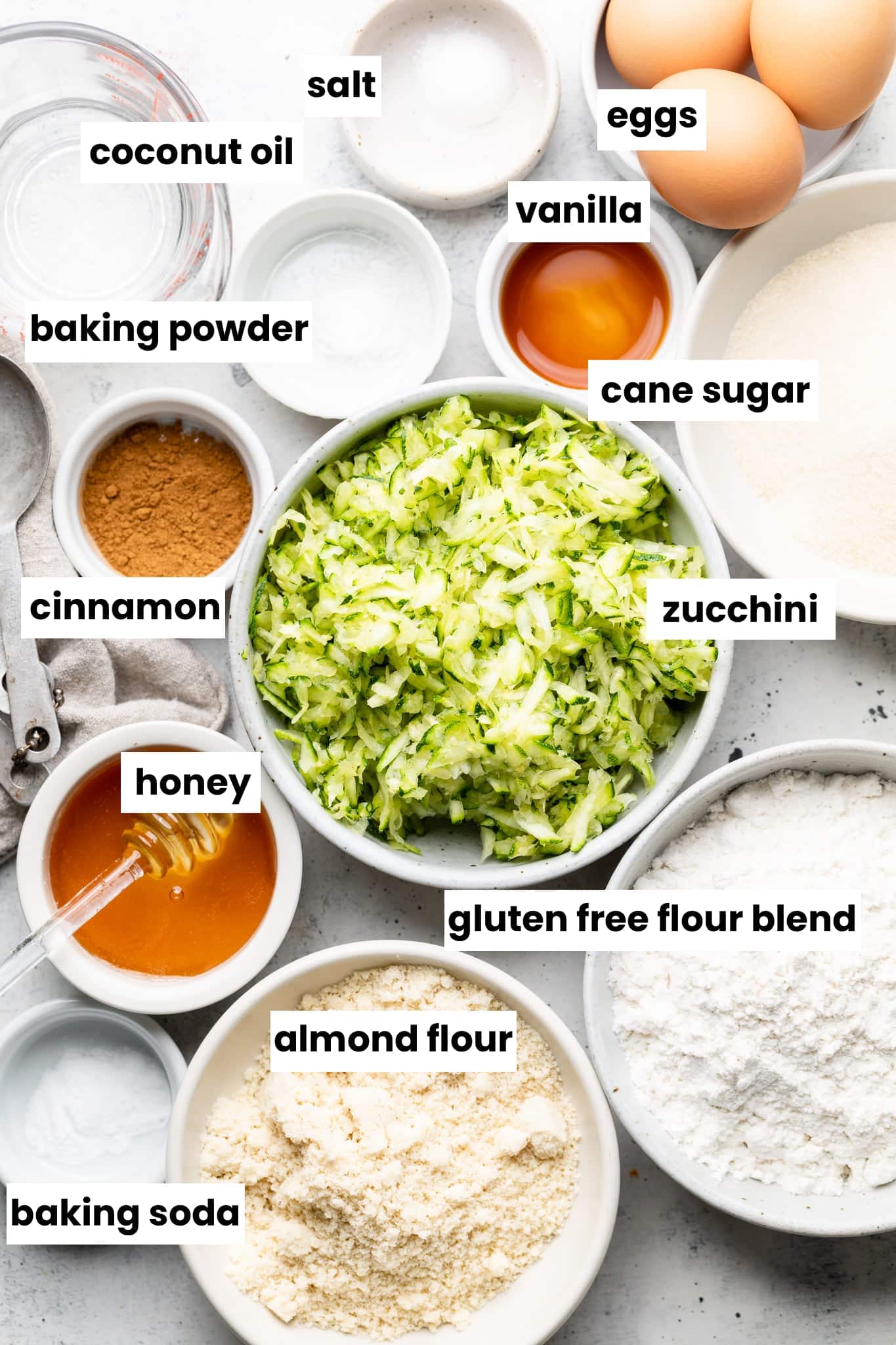 Ingredients for the zucchini bread, including zucchini, honey, gluten free flour, coconut oil, and spices.