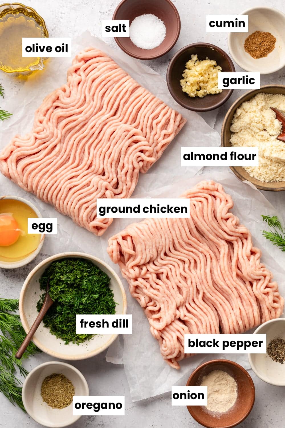 All of the ingredient needed in the recipe, including ground chicken, almond flour, garlic, cumin, salt, olive oil, egg, dill, oregano, onion, and black pepper.