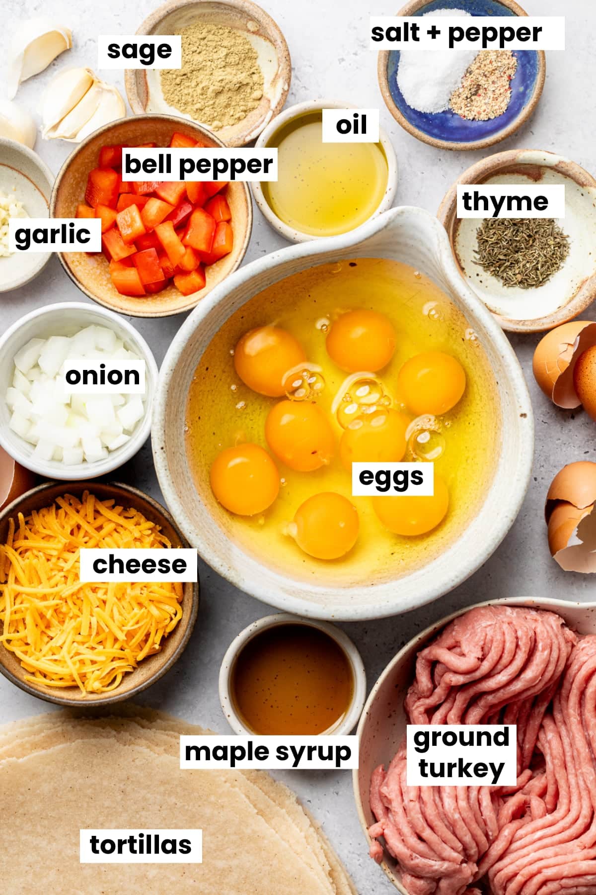 Ingredients in the recipe, including burrito wraps, eggs, ground turkey, maple syrup, cheese, thyme, onion, bell pepper, garlic, salt, pepper, sage, and garlic.