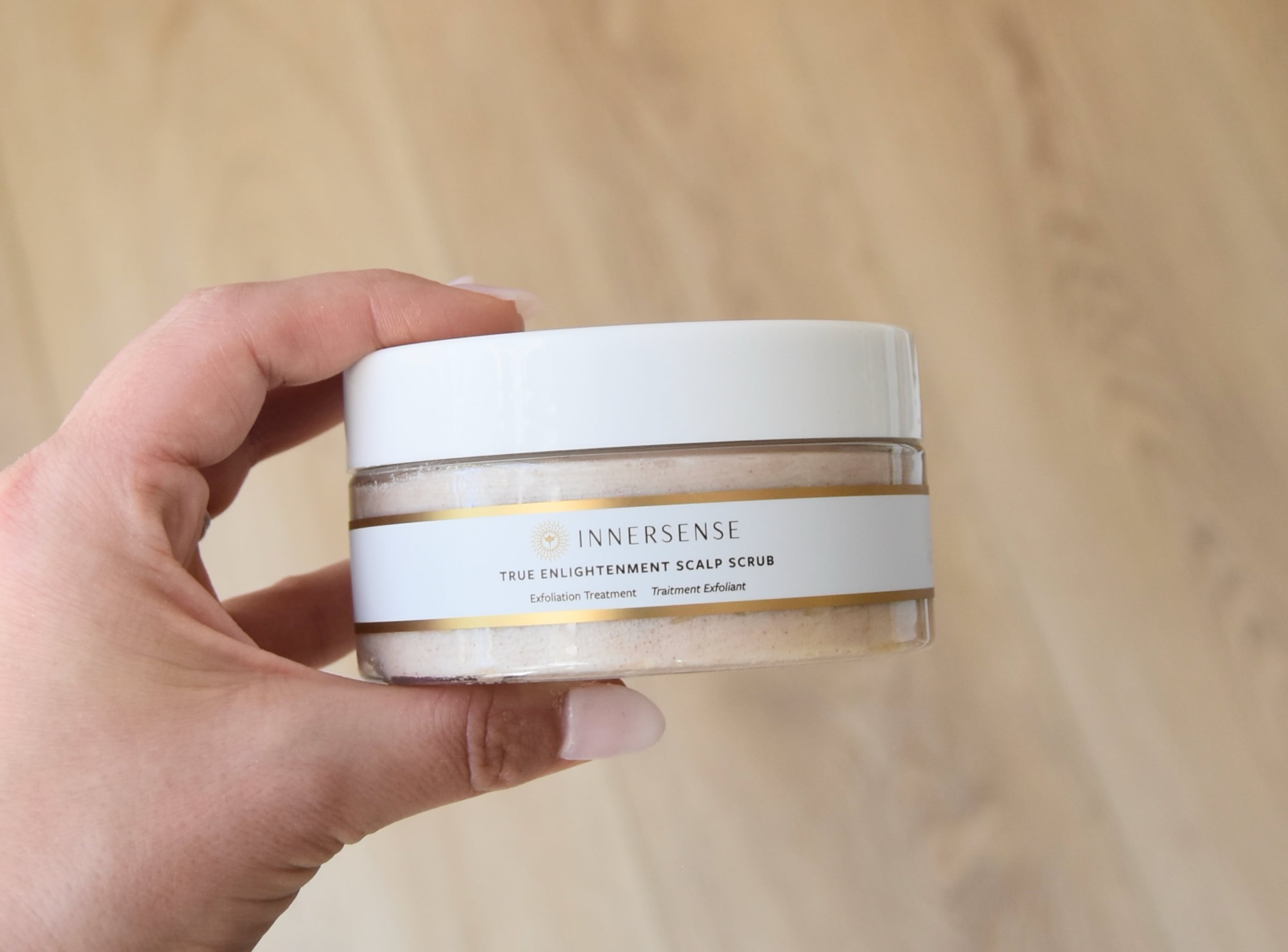 Holding a jar of the Innersense True Elightenment Scalp Scrub.