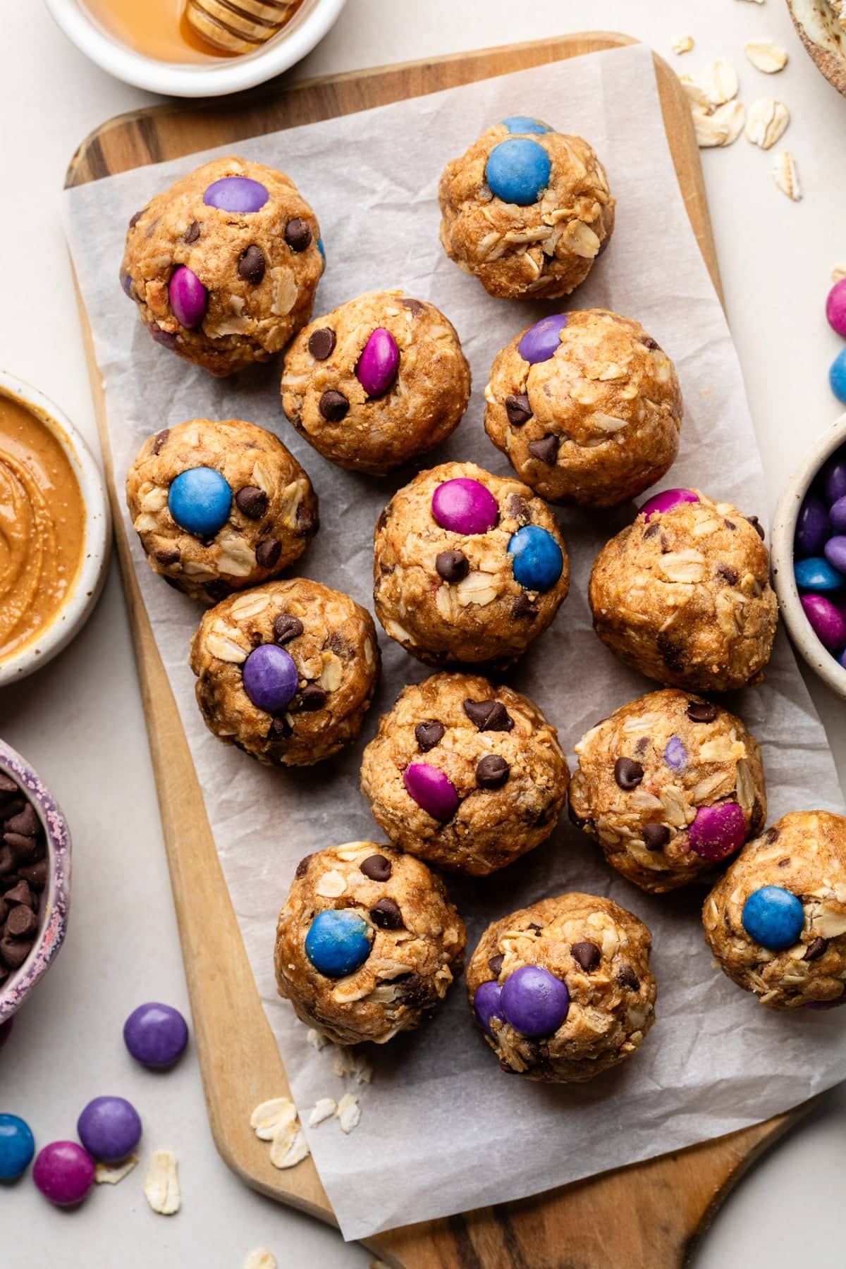 Monster cookie protein balls that have been chilled and are on a serving platter with extra chocolate chips and chocolate pieces.
