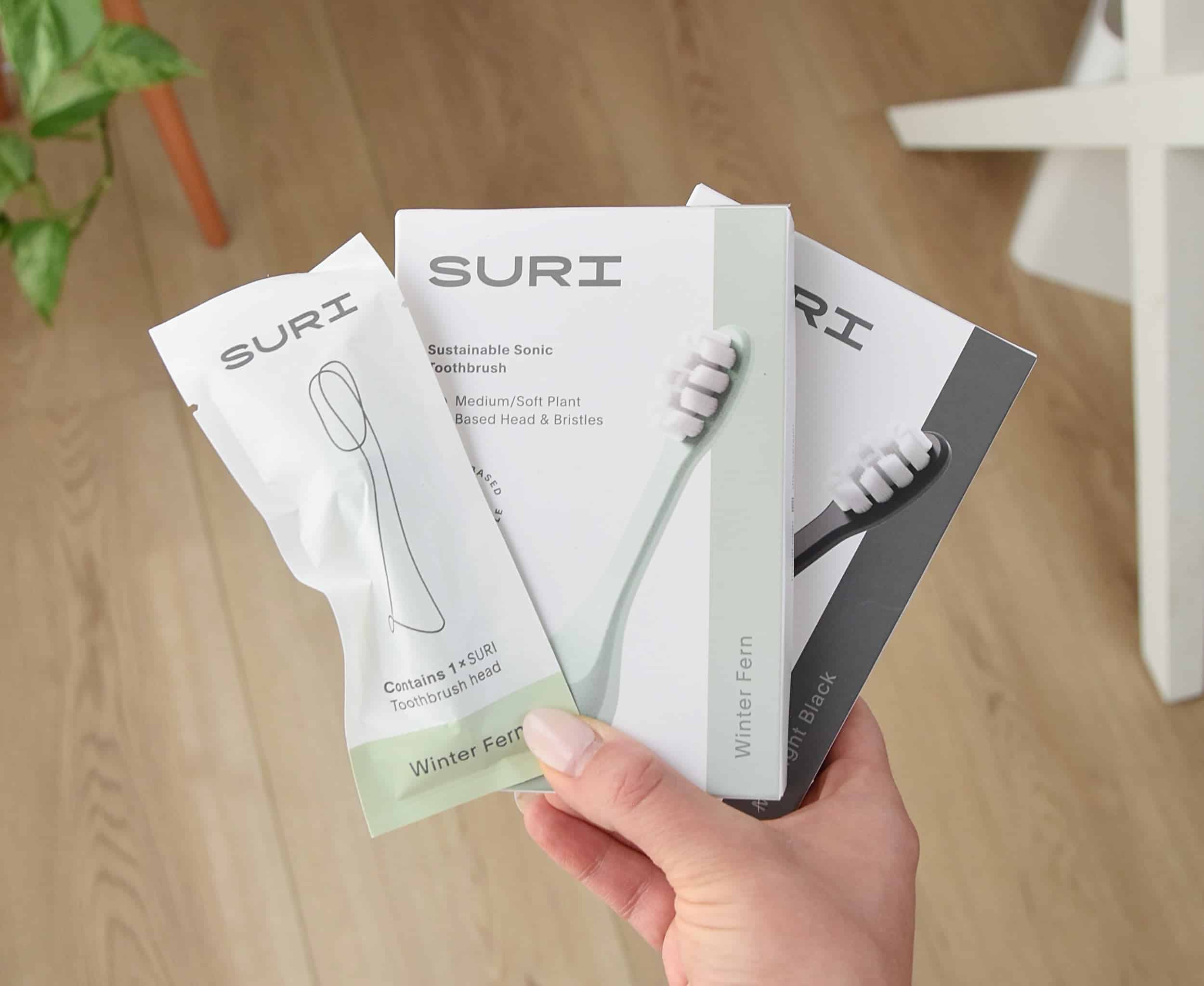 Holding the SURI toothbrush head replacement packs.