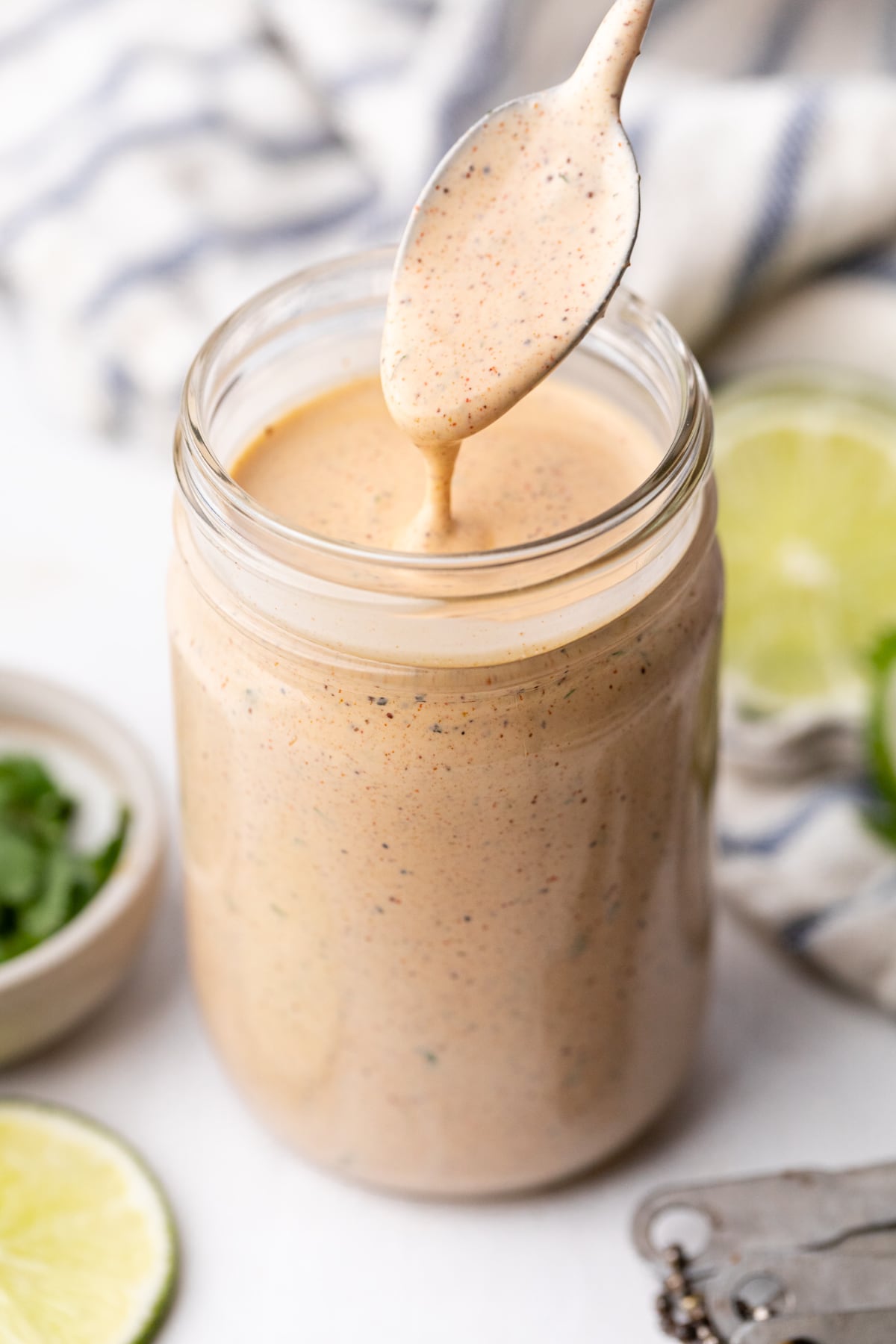 A mason jar with homemade southwest salad dressing being mixed with a spoon.