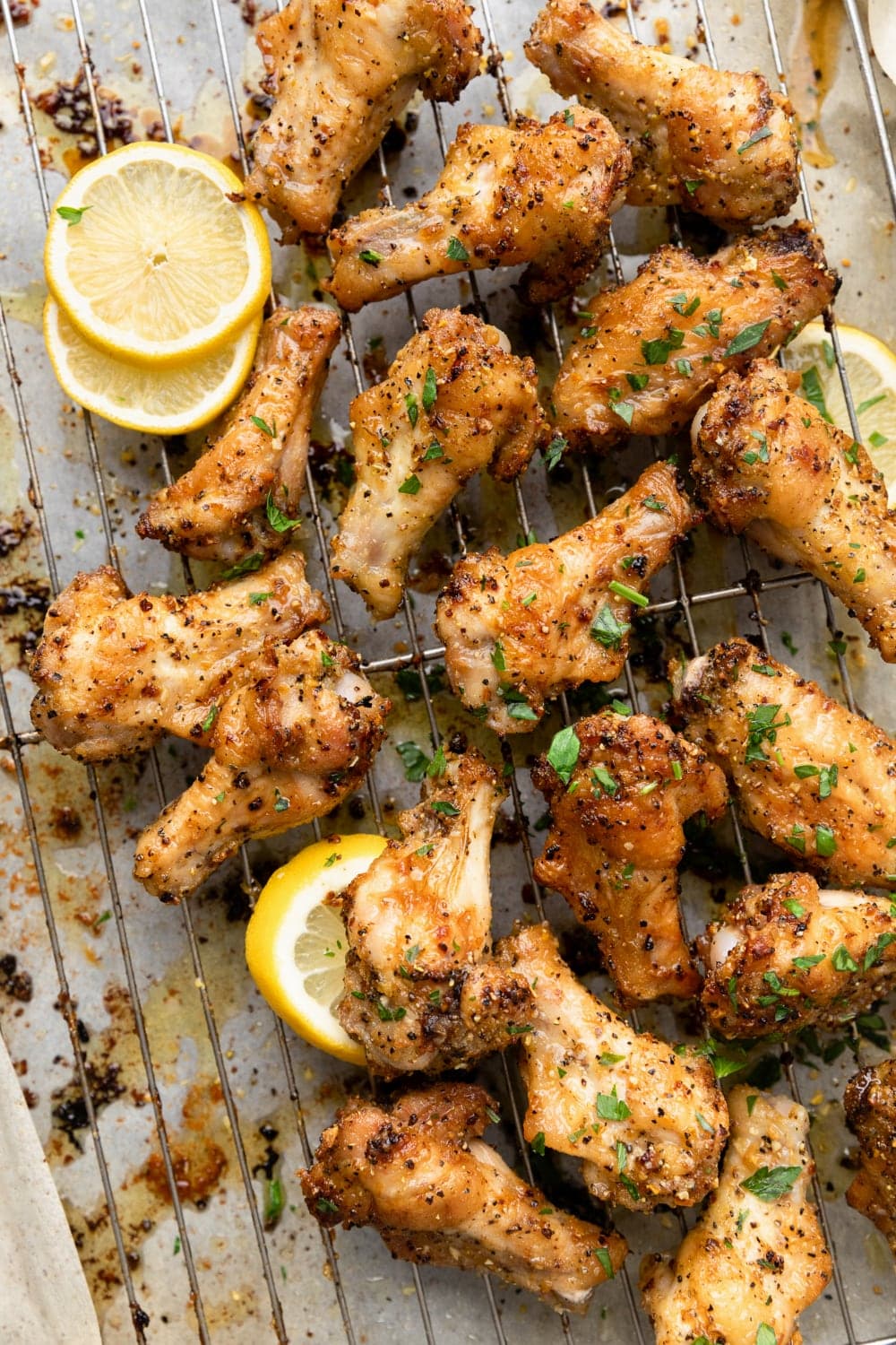 Baked lemon pepper chicken wings on a wire rack with lemon and parsley.