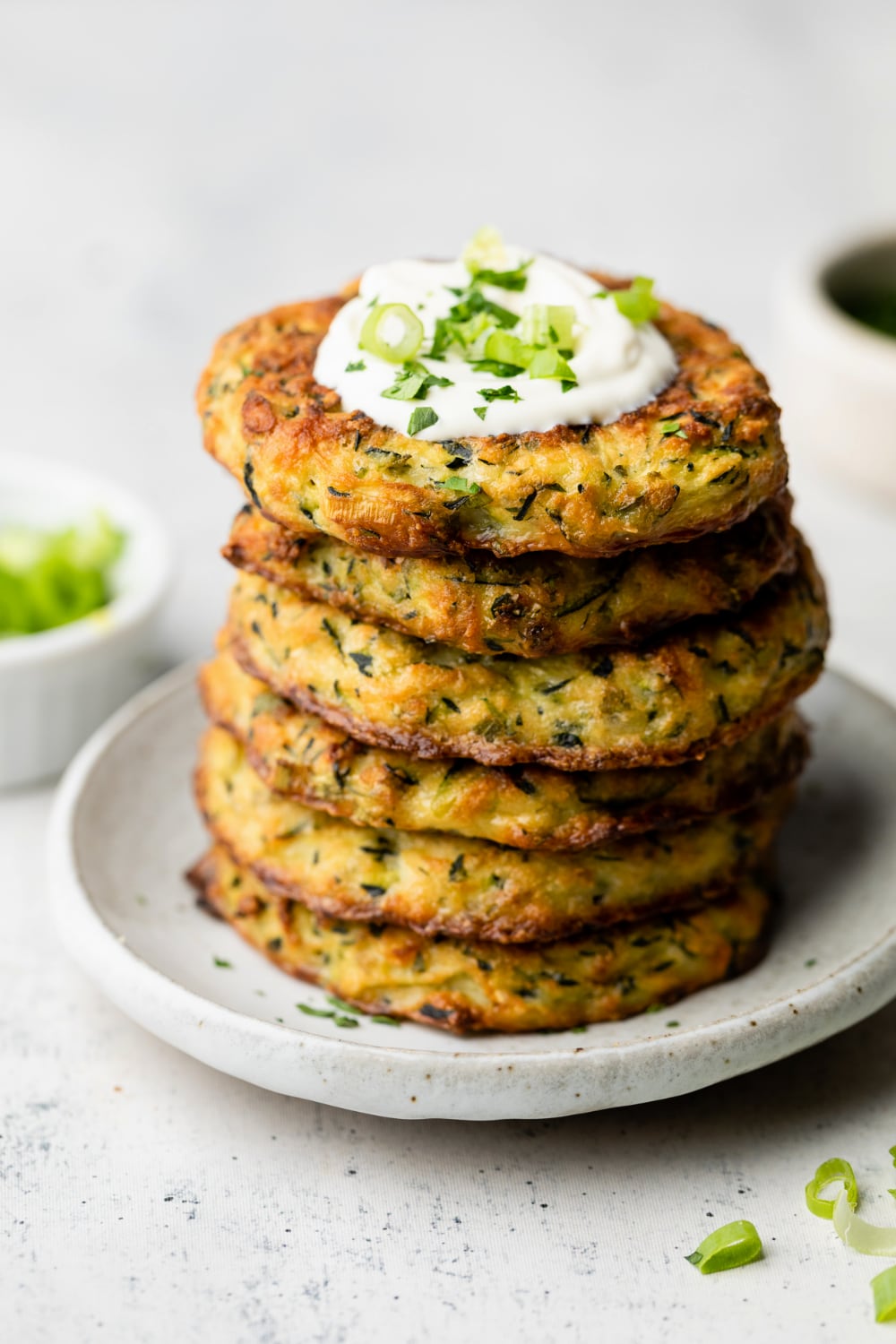 A stack of baked zucchini fritters with toppings.