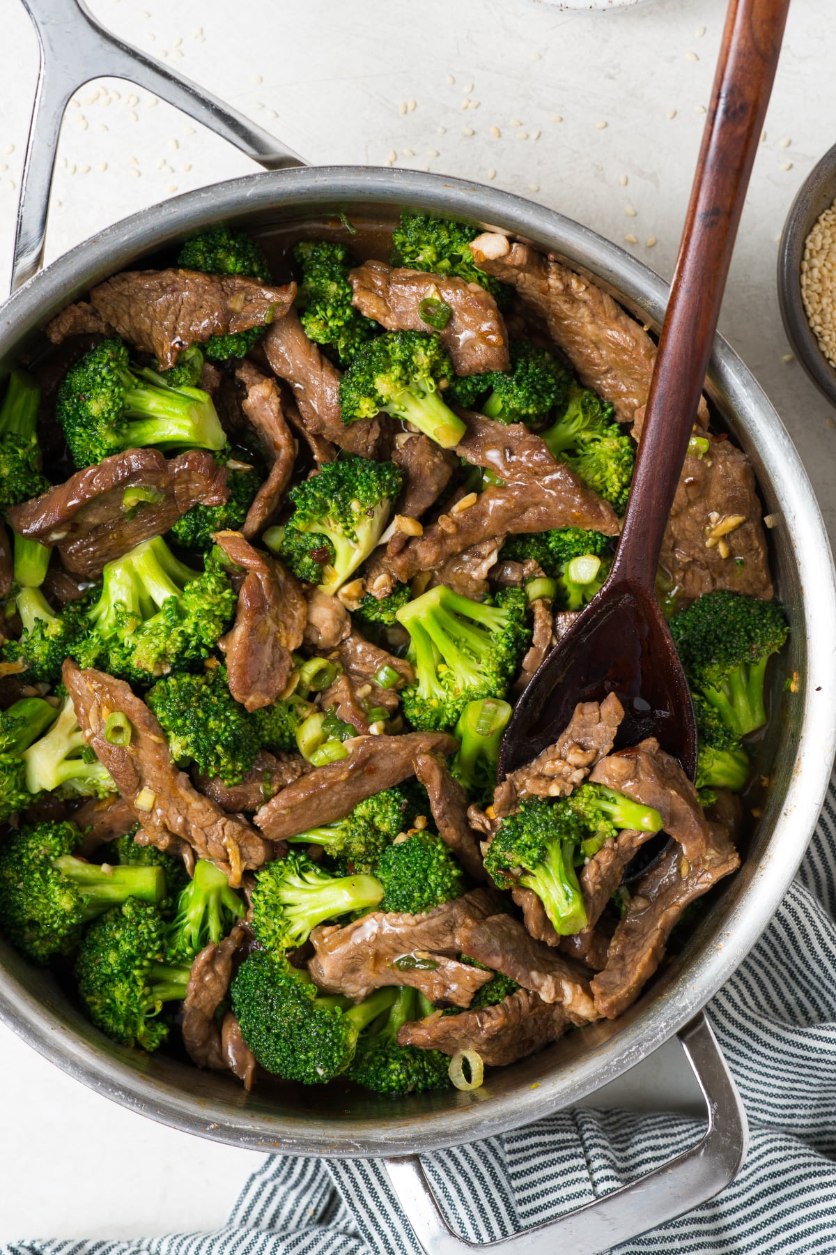 A skillet with the stir fry inside and a large spoon ready to serve.