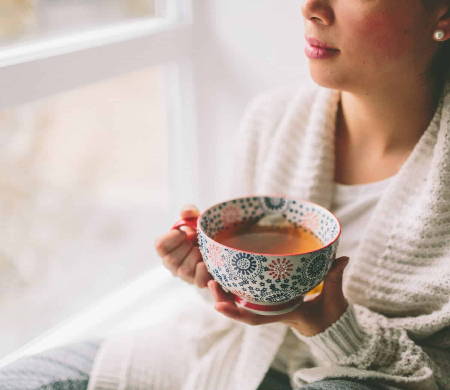 A woman resting drinking a cup of tea trying to rest and recover from hpa axis issues. 