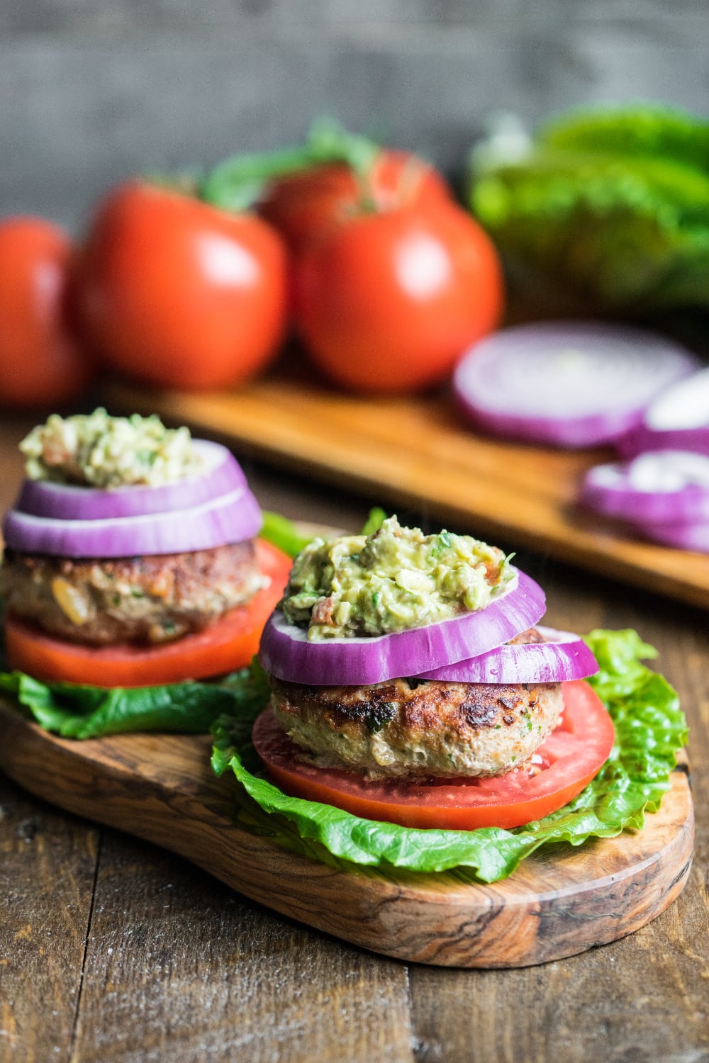 A paleo turkey burger on a platter ready to be served with tomatoes and lettuce wraps.