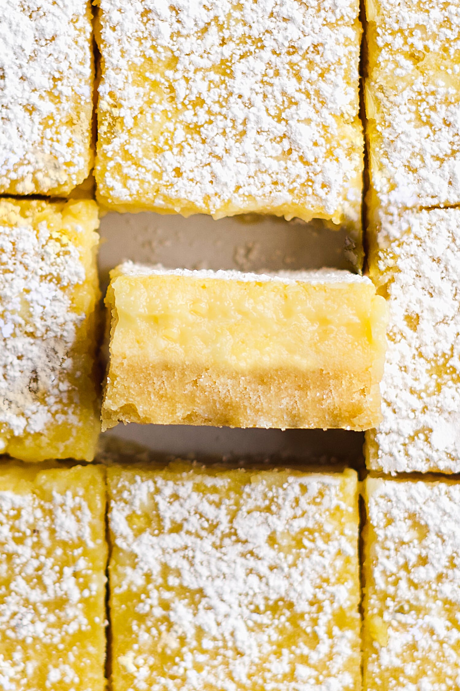 A healthy lemon bar turned on its side to show the crust and the filling. 