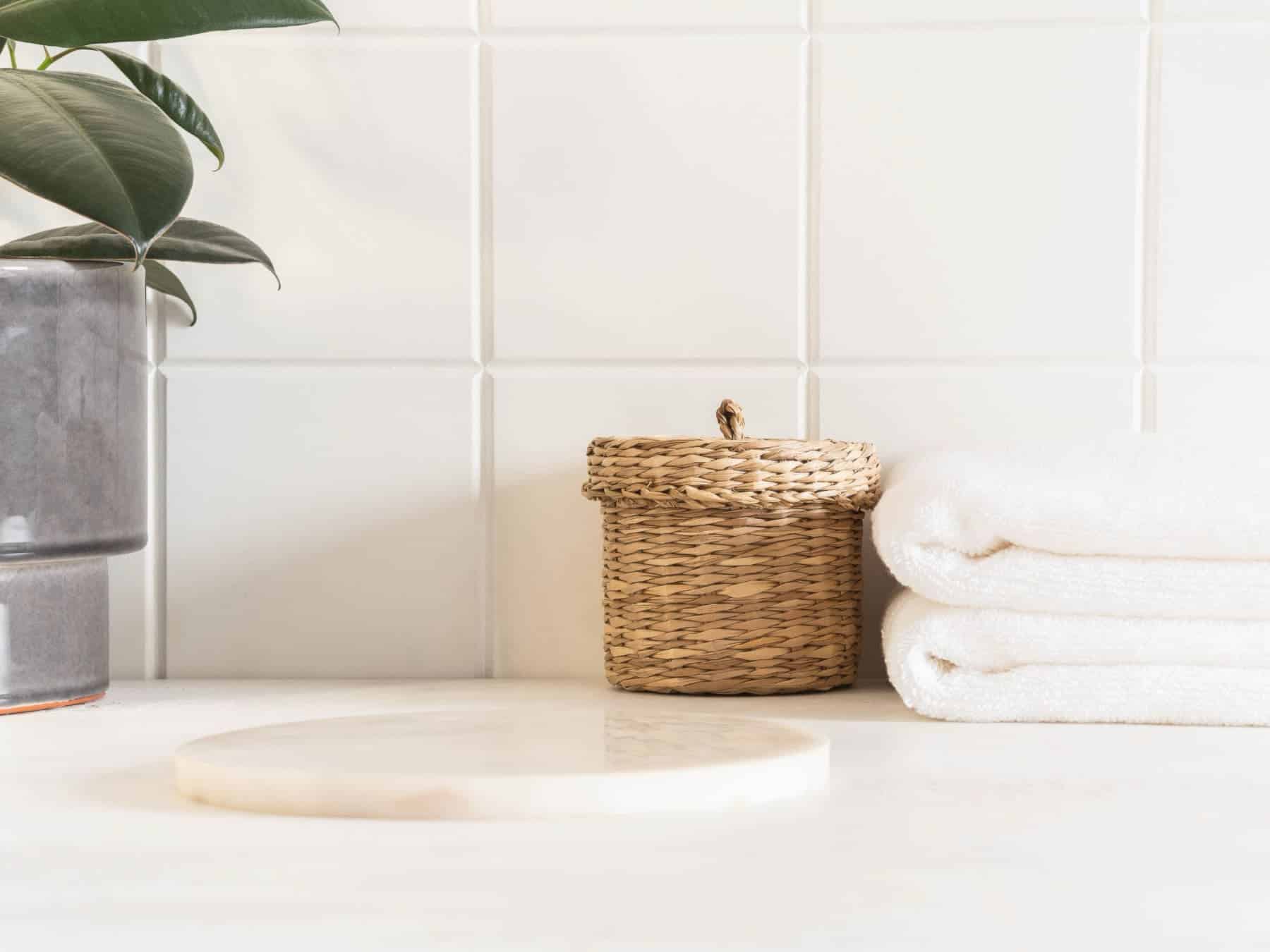A small jar on the counter in the bathroom with cotton round pads to apply skin care products.