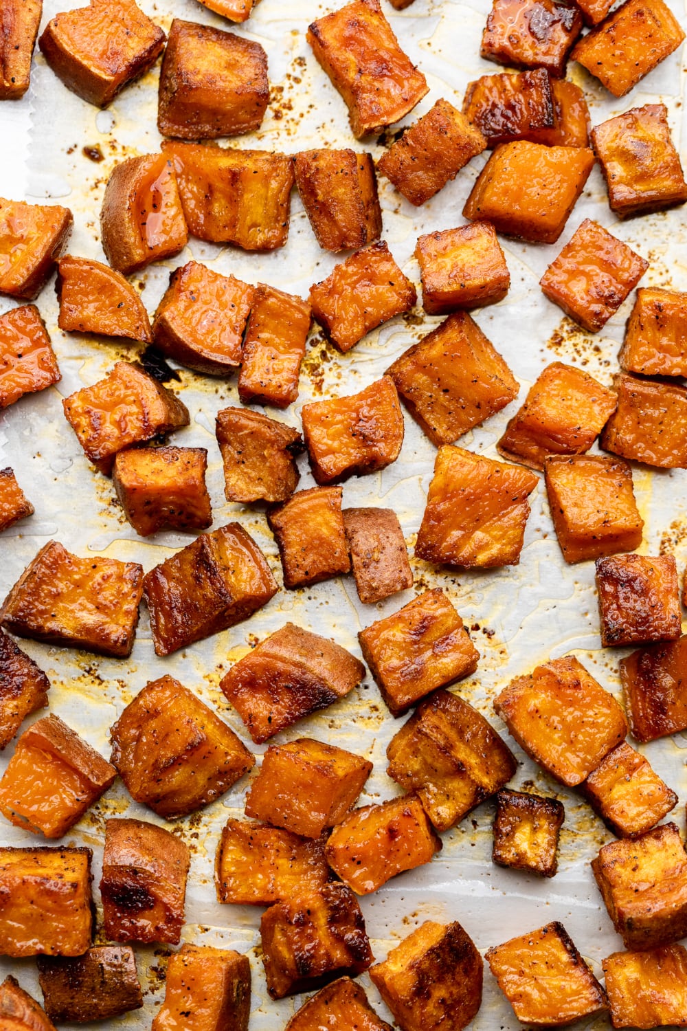 Super crispy sweet potatoes on a sheet pan with parchment paper.