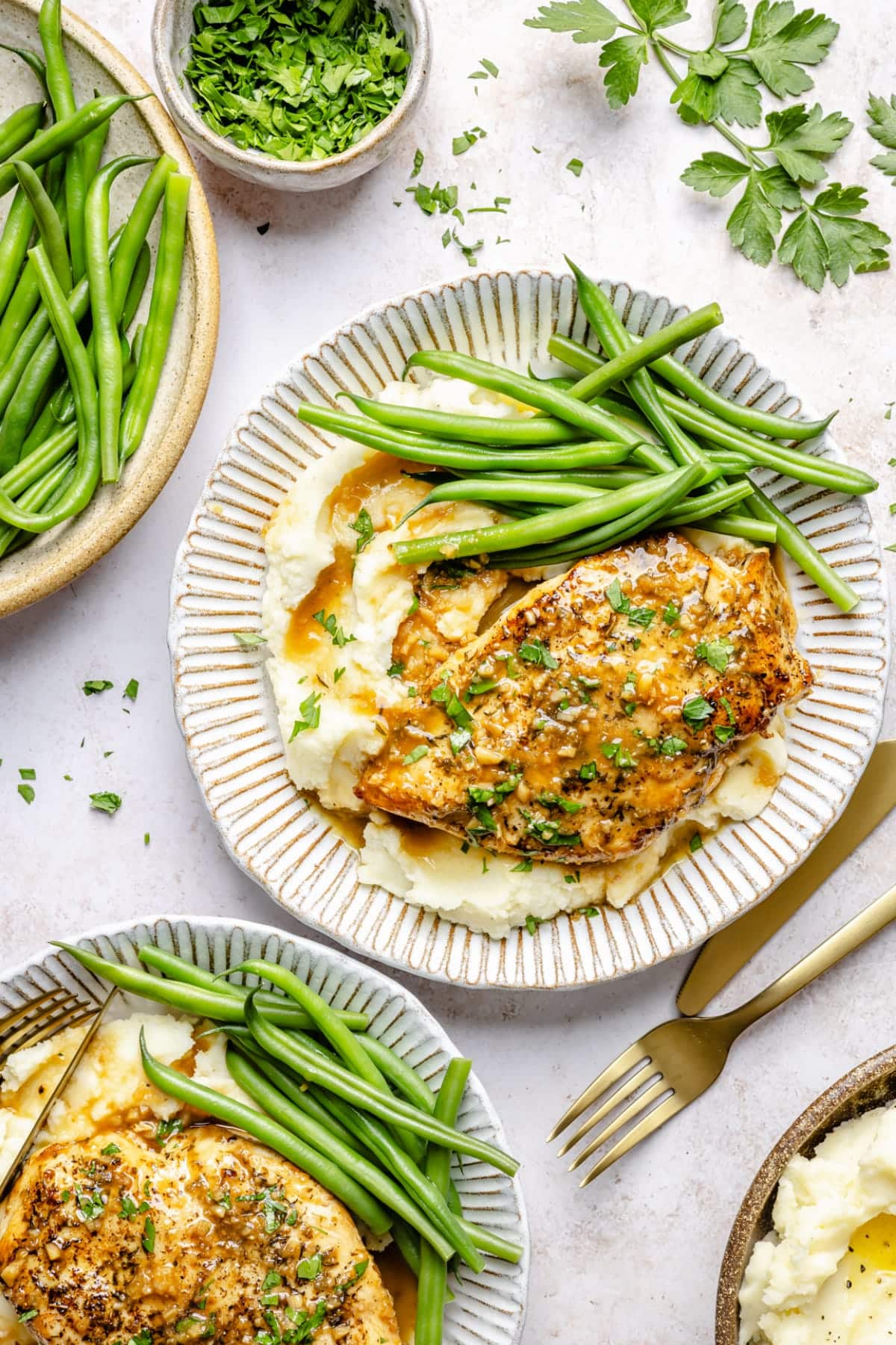 The chicken served over potatoes and with green beans on a plate with a fork.