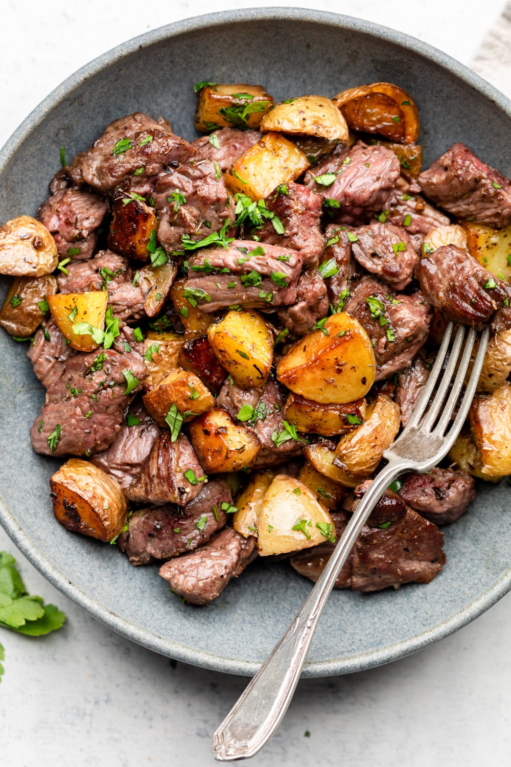 Close up of a plate with garlic butter steak bites and potatoes and a fork.
