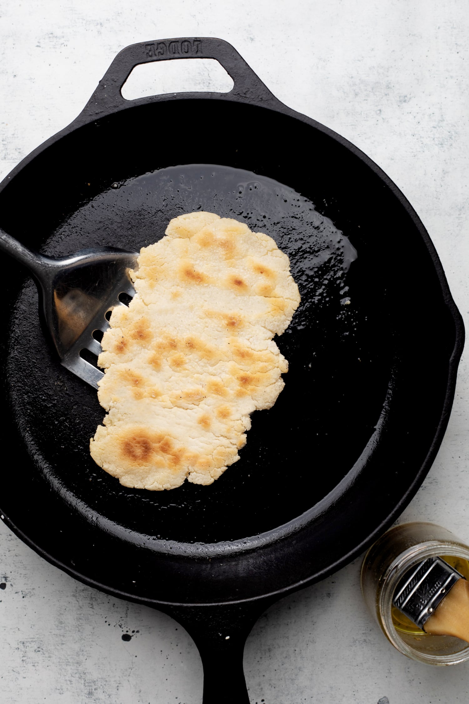 cooking gluten free naan bread in a cast iron pan