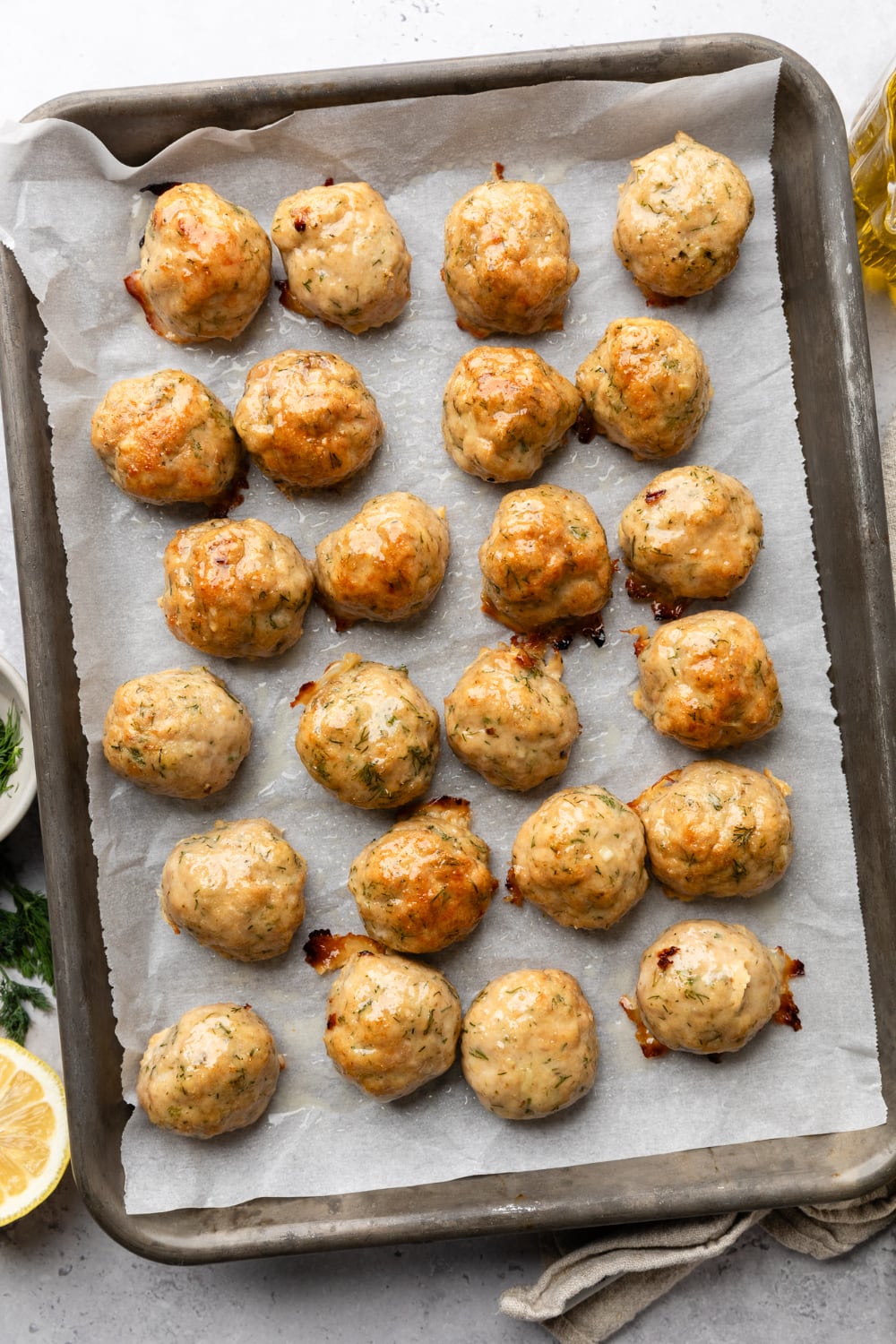 A pan with 24 Greek chicken meatballs on it roasted in the oven.