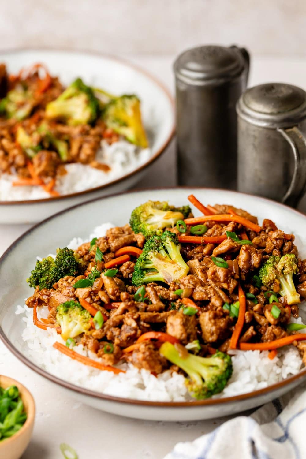 A close up of ground turkey teriyaki with broccoli and carrots over a bowl of rice.