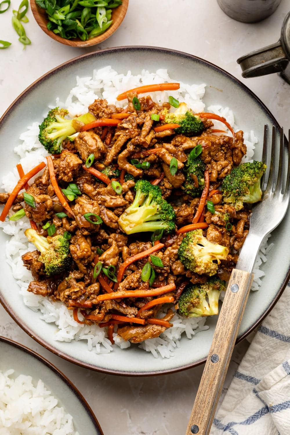 A bowl of rice with ground turkey teriyaki on top and a fork on the side for eating.