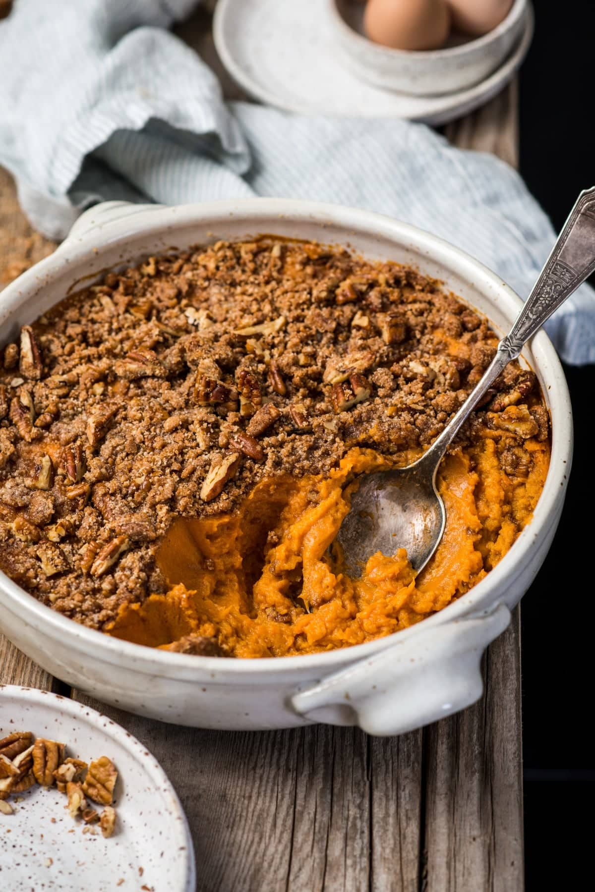 A large spoon in the sweet potato casserole made with healthier ingredients scooping it out to be served at dinner.
