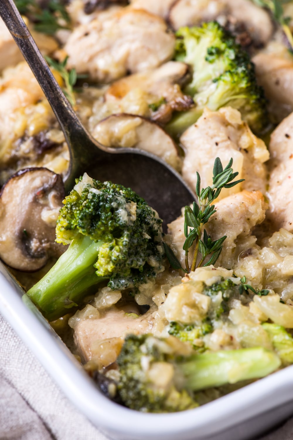 A spoon scooping out chicken and broccoli from the casserole dish.
