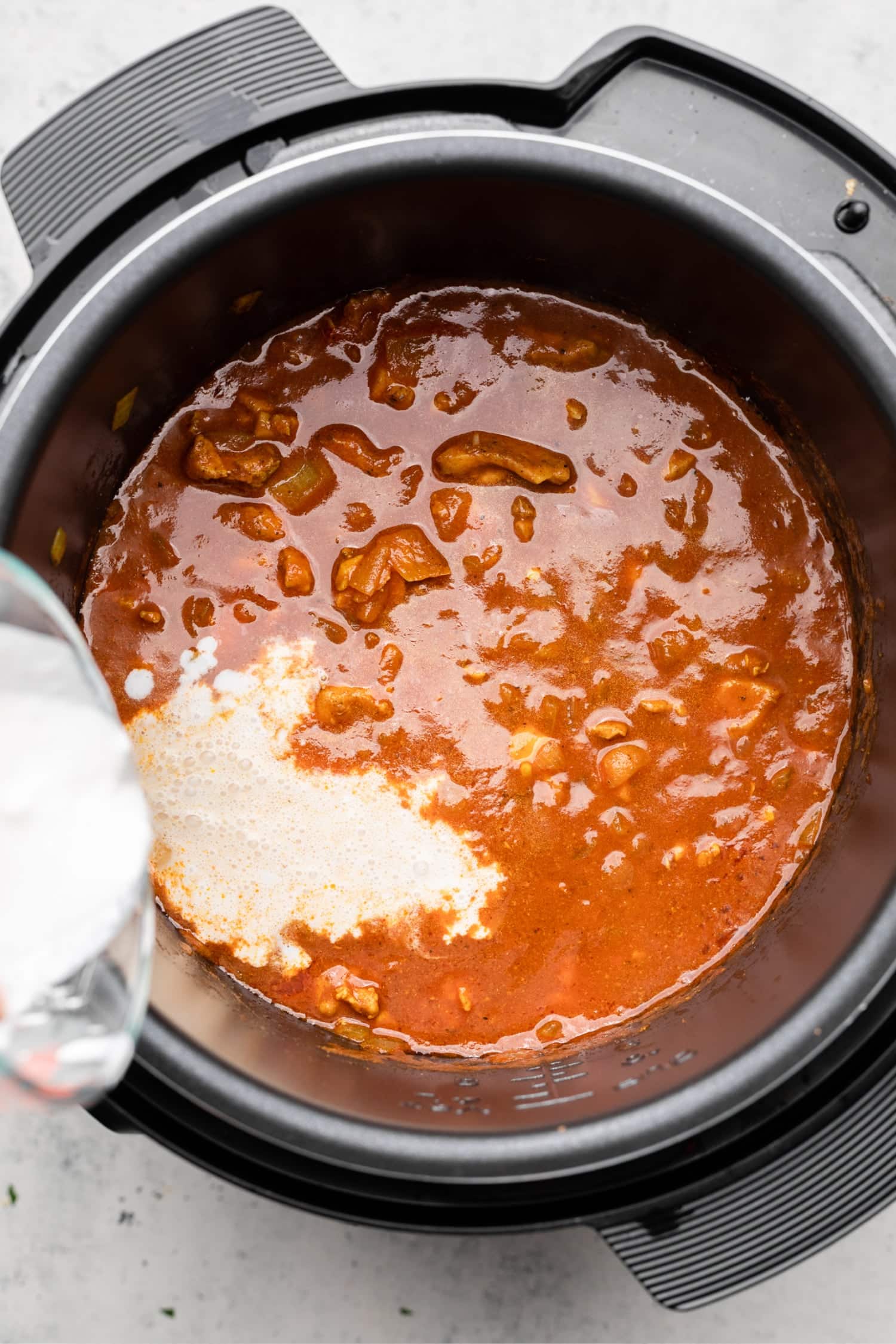 Adding the yogurt to the simmered curry dish in the instant pot.