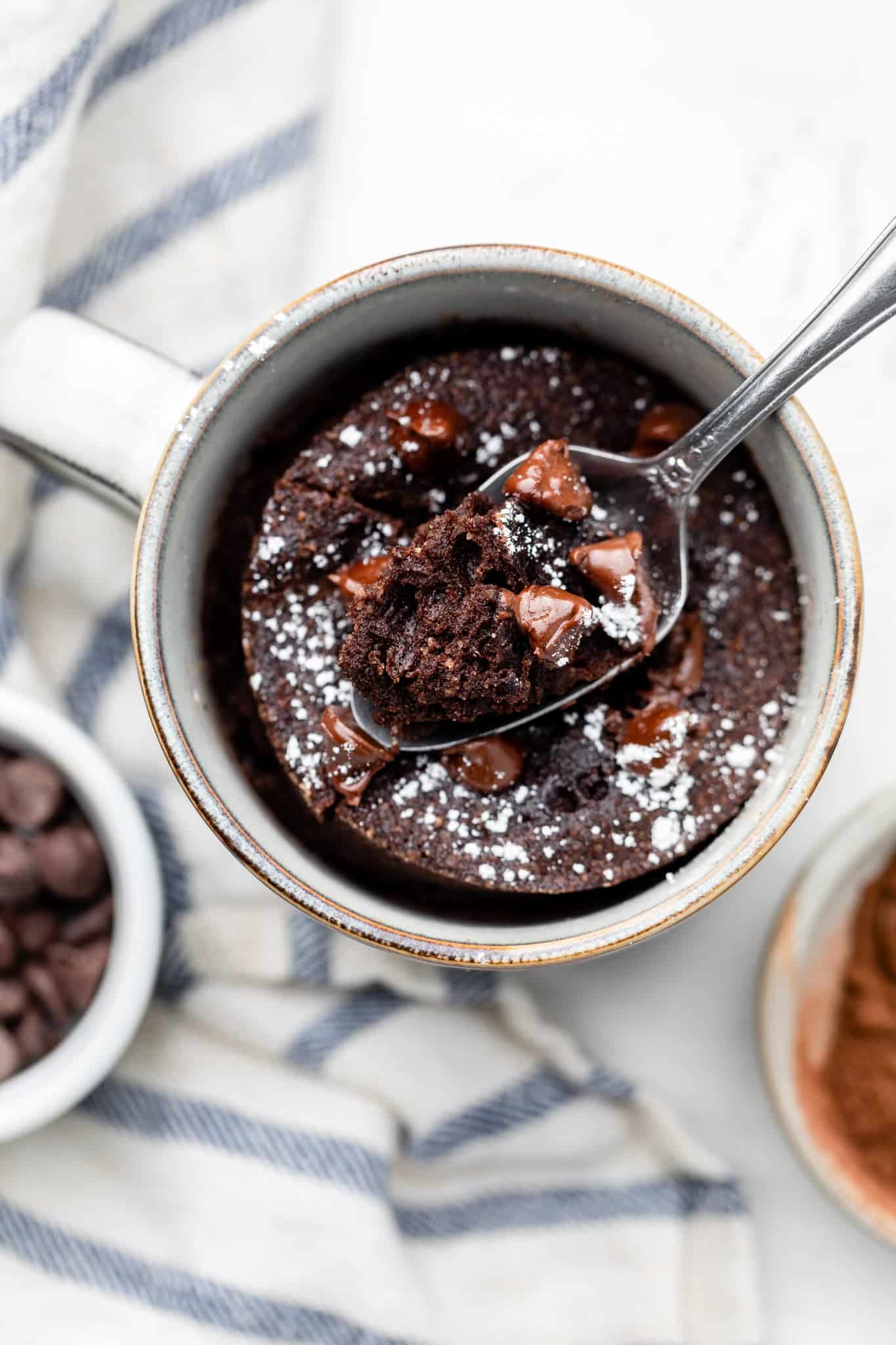 The healthy mug cake recipe cooking in a mug with a big spoonful taken out.