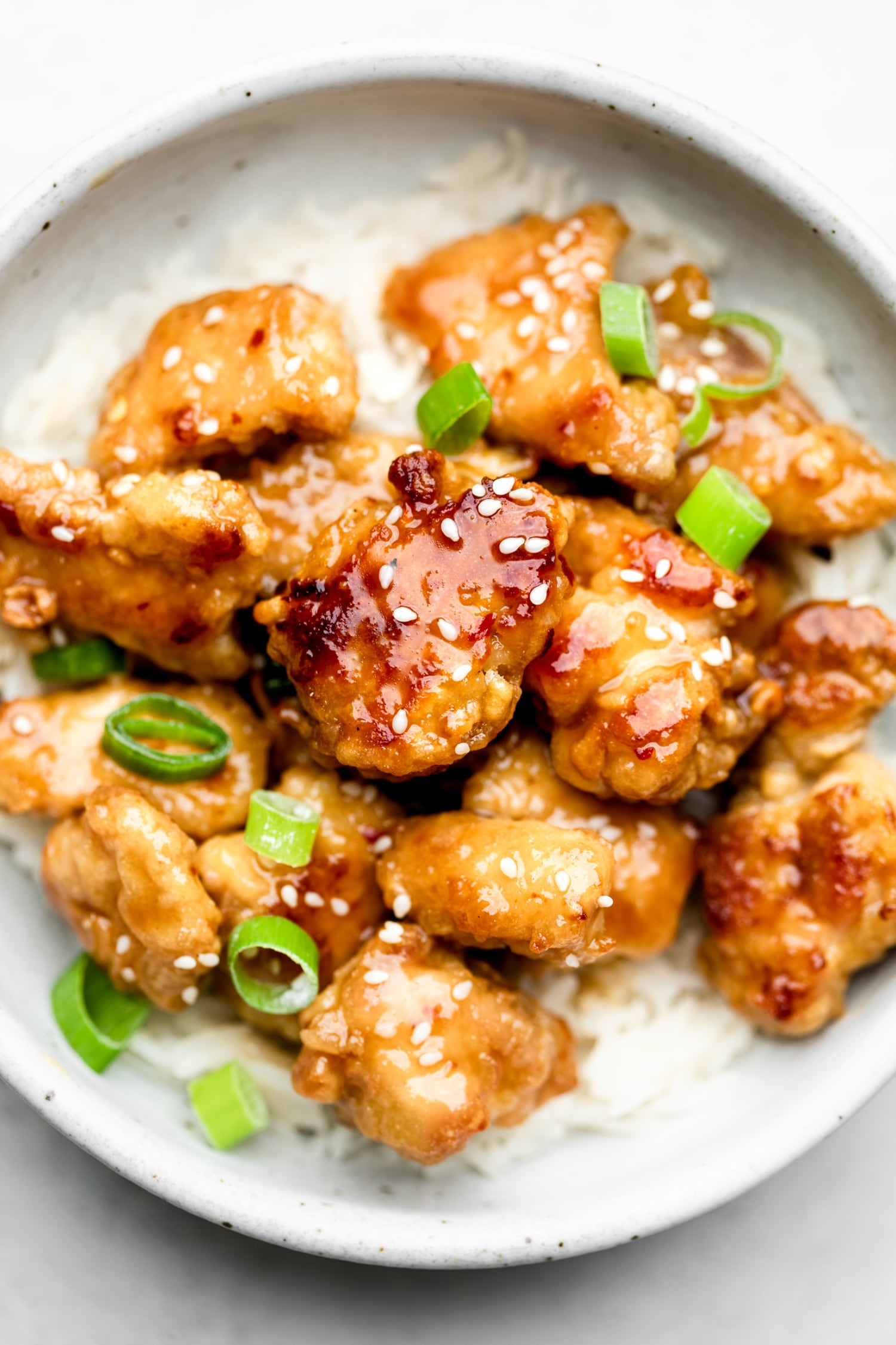 Orange chicken pieces in a bowl over rice.
