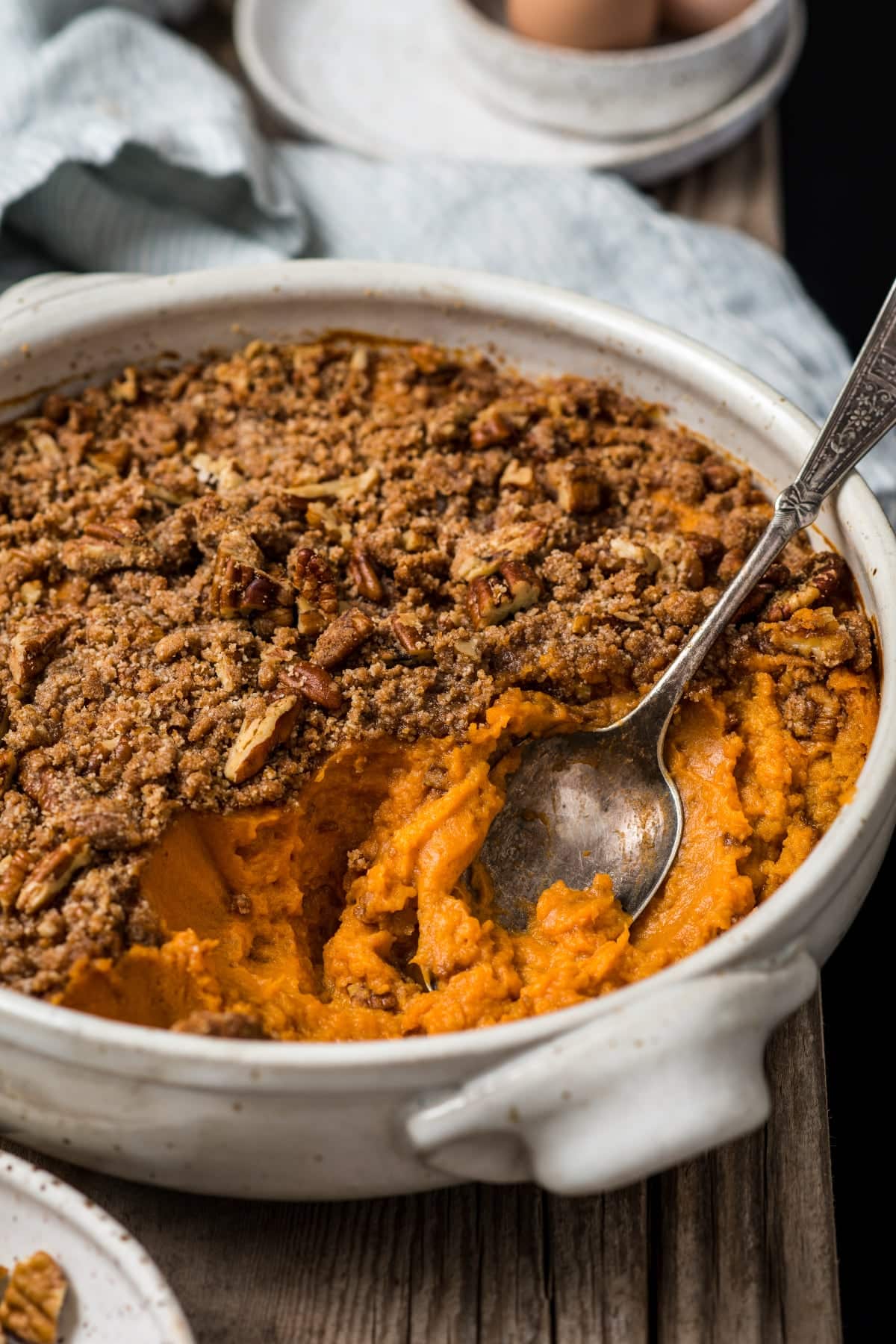 A healthy sweet potato casserole in a large serving dish with a spoon ready for serving on a Thanksgiving table.