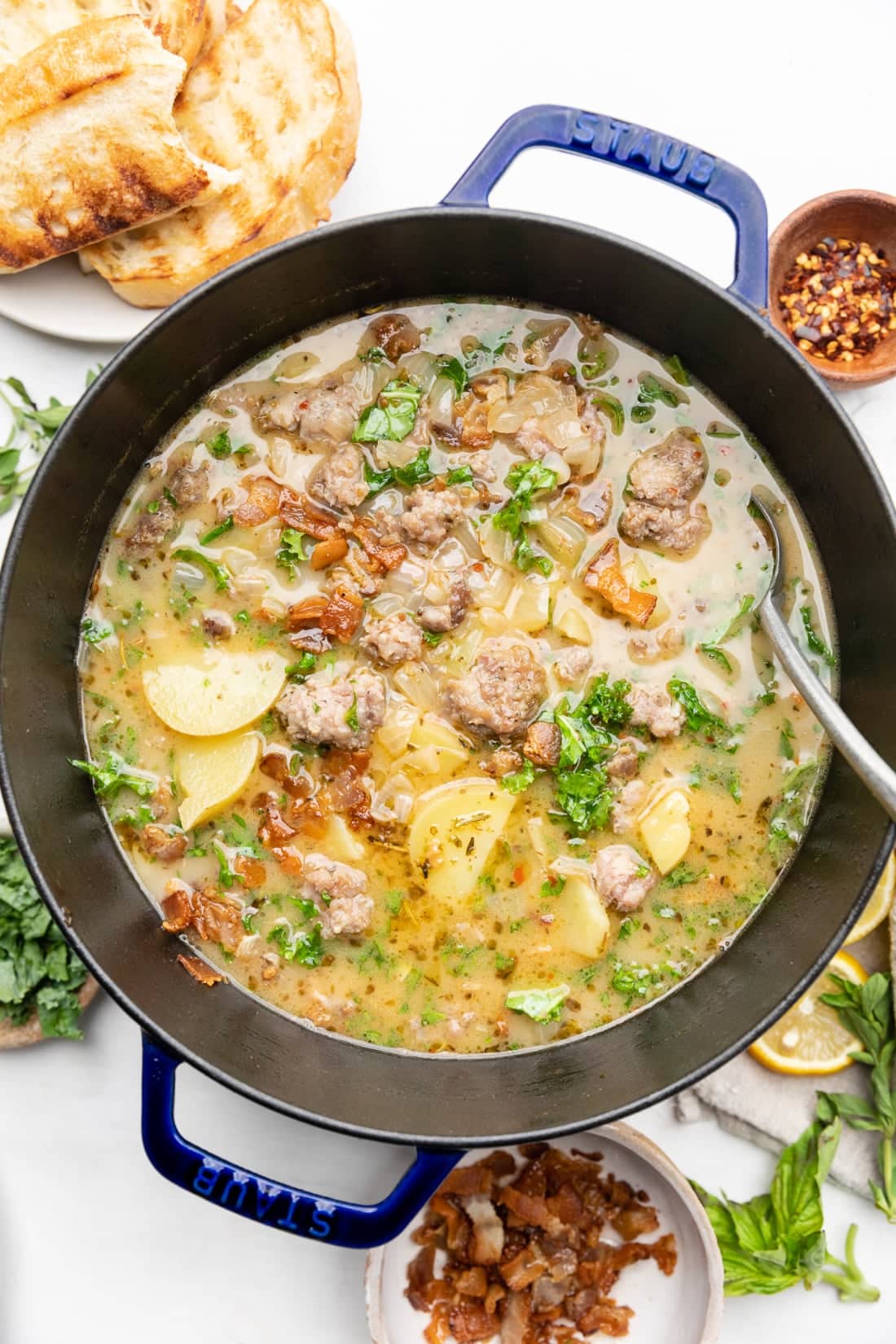 A large soup pot with healthy zuppa toscana in it and a spoon for serving.