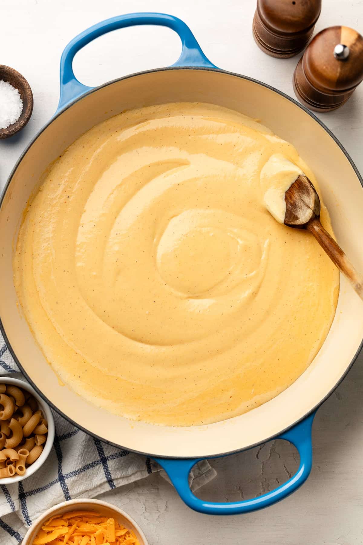 A pan with the heated cheese sauce and a spoon stirring the sauce.