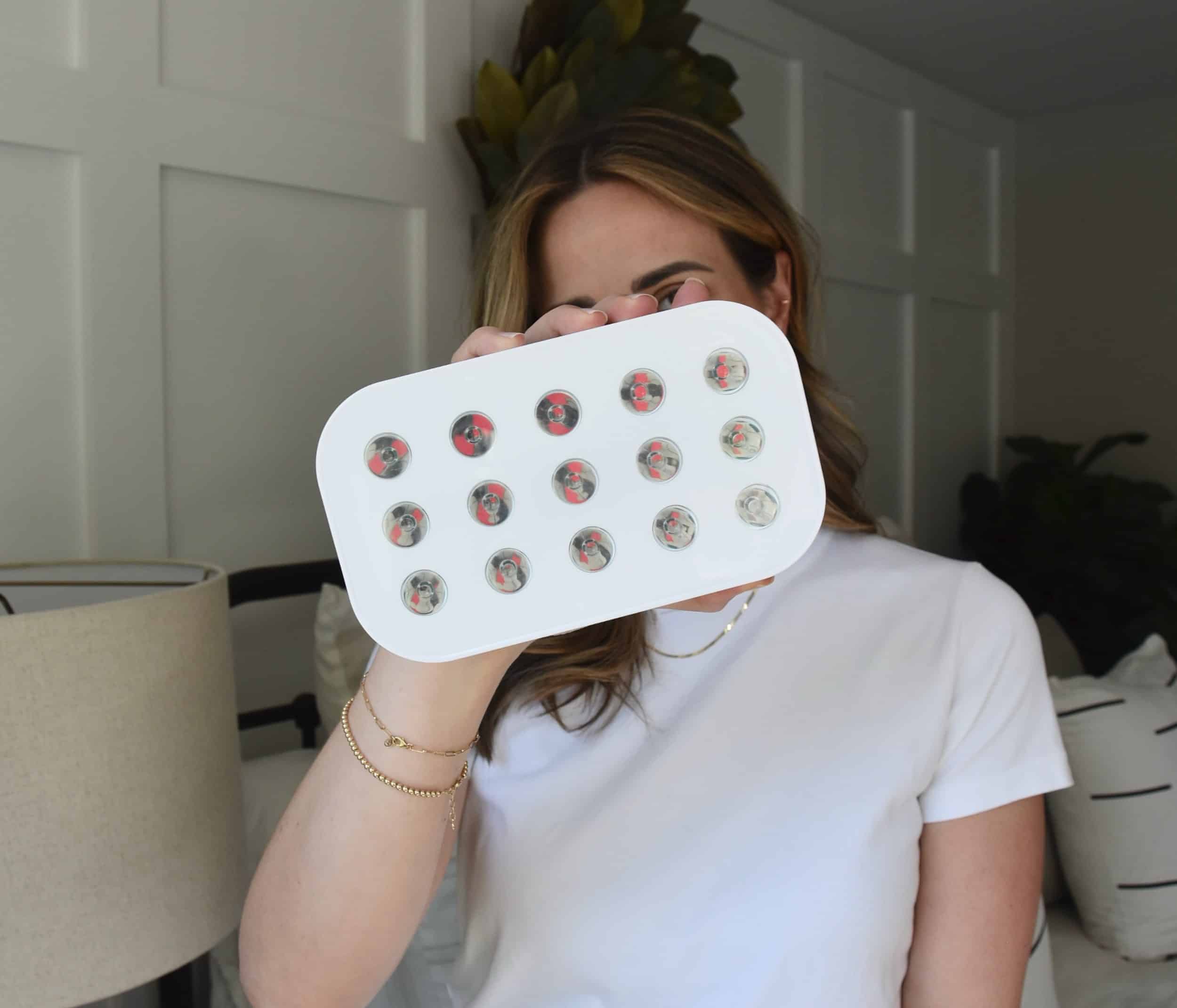 Holding the Lumebox red light therapy device in one hand to review the benefits.