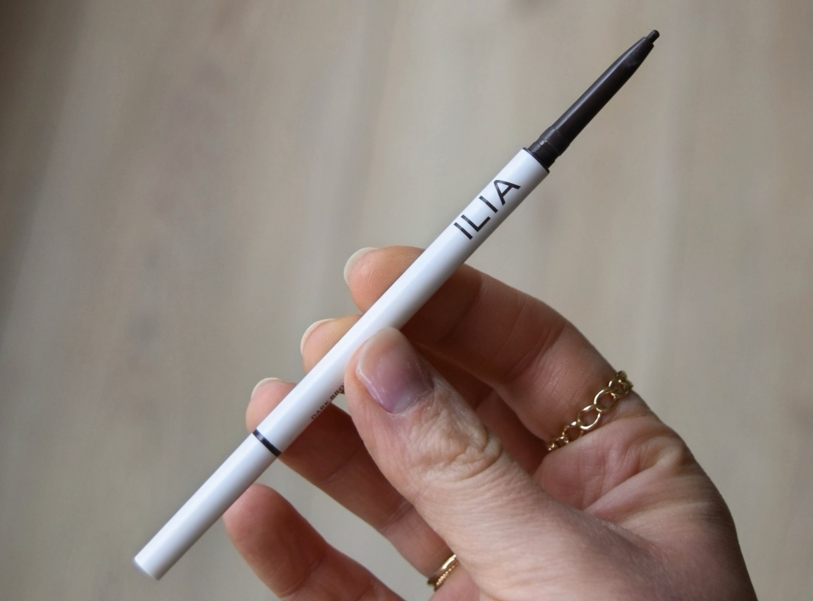 Holding the Micro-Tip Brow Pencil with the top off to show the shade.