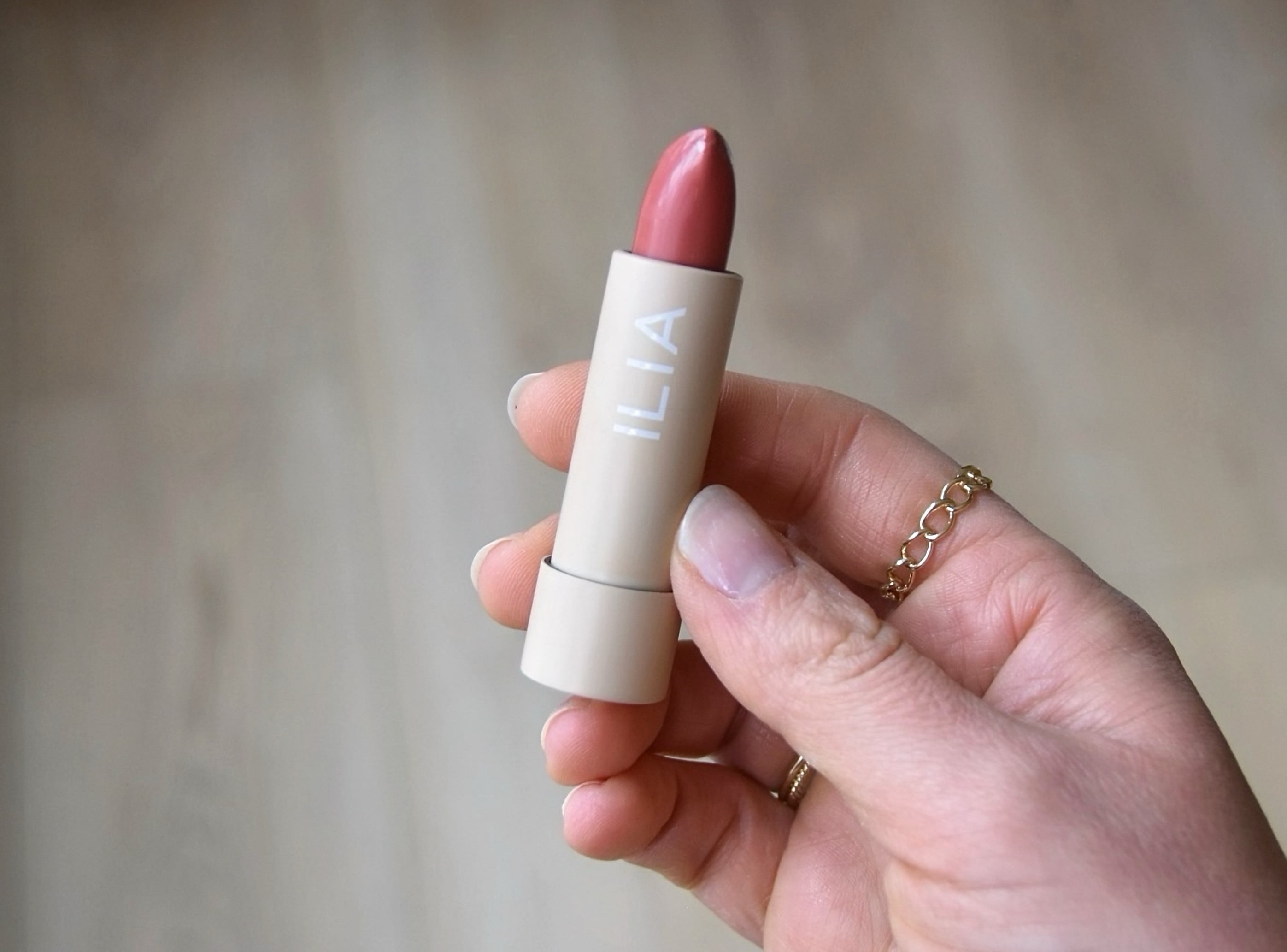 Holding the color block lipstick in amberlight with the top off to show the shade.