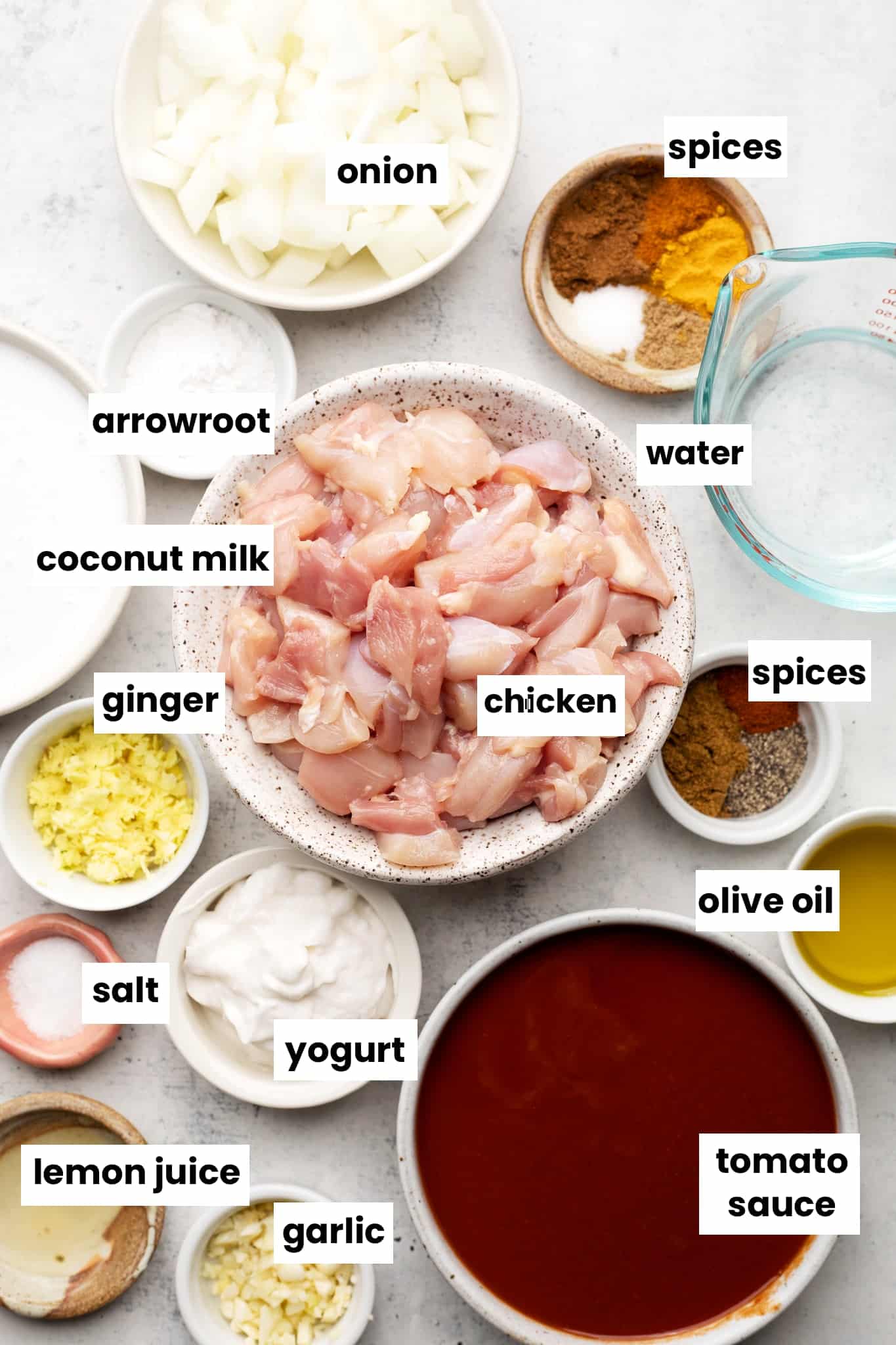 Healthy ingredients for chicken tikka masala, including chicken, garam masala, lemon juice, garlic, tomato sauce, olive oil, yogurt, water, ginger, coconut milk, onion, arrowroot, and spices.