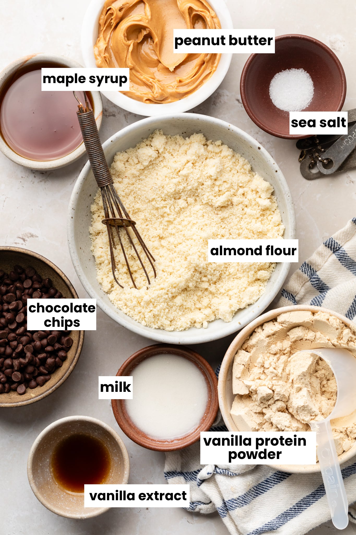 Ingredients in the recipe, including almond flour, chocolate chips, sea salt, peanut butter, maple syrup, peanut butter, milk, vanilla protein powder, and vanilla extract.