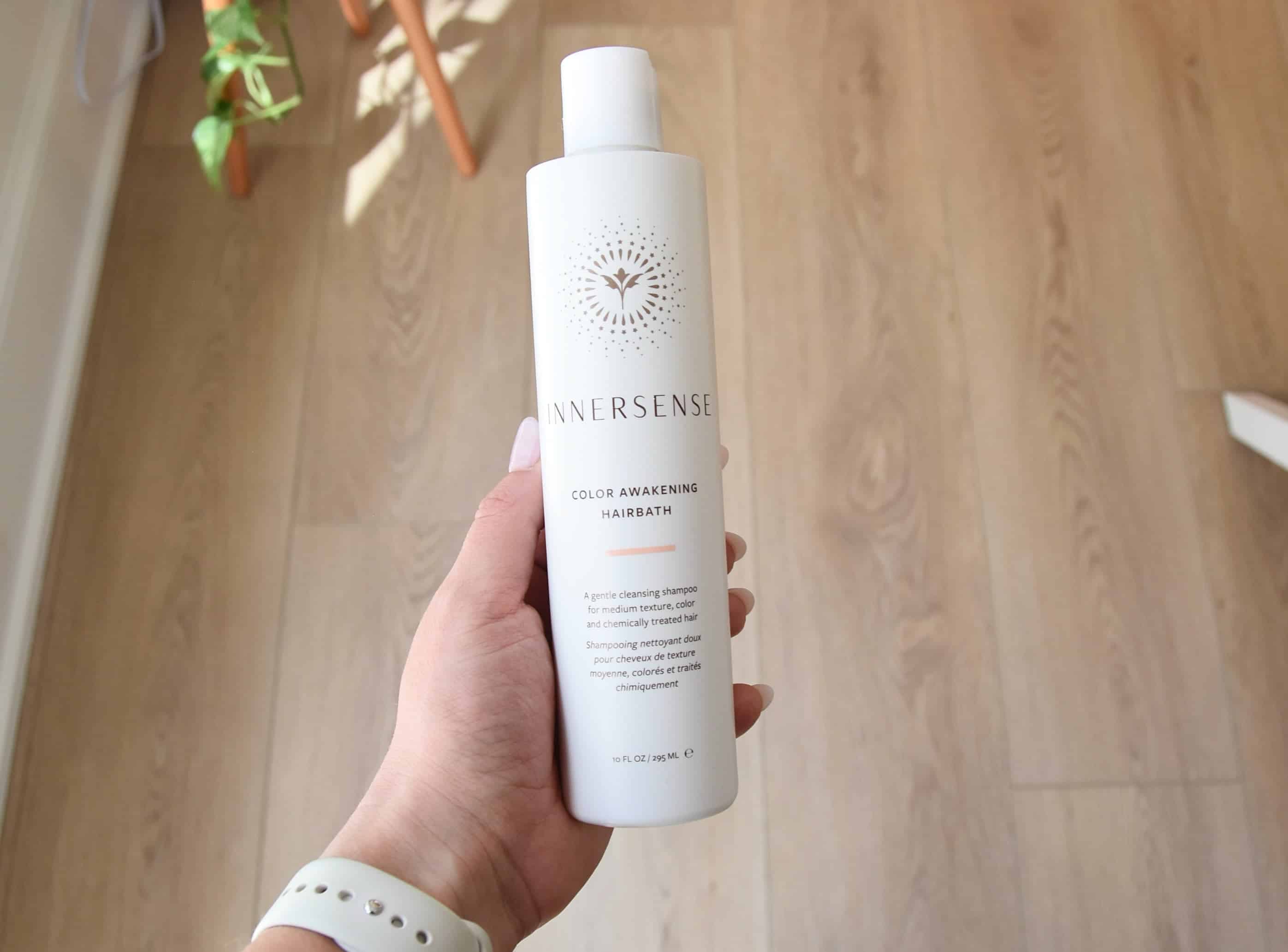 Holding a bottle of the Innersense Color Awakening Hairbath.
