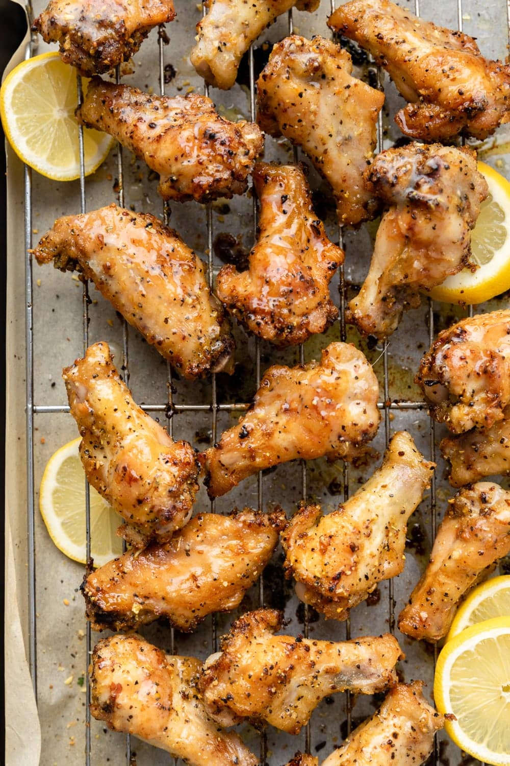 Chicken wings with lemon pepper seasoning on a roasting rack.