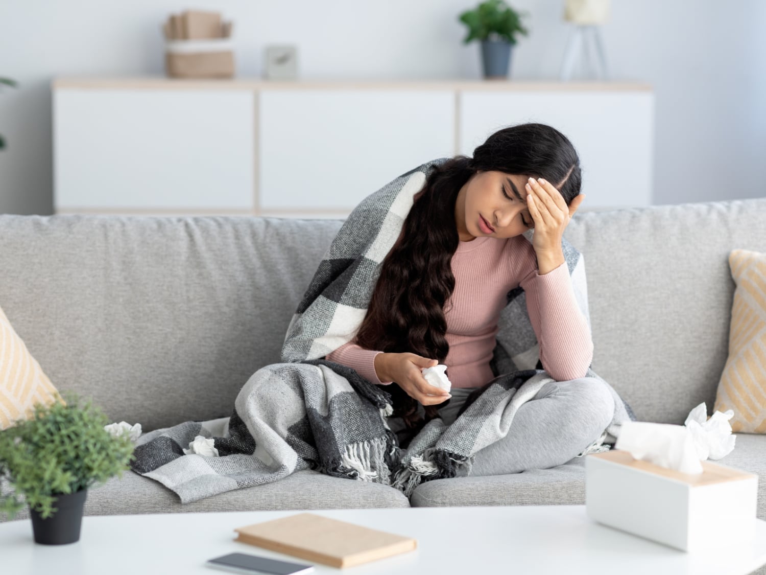 Woman sitting on the couch with seasonal allergy symptoms.