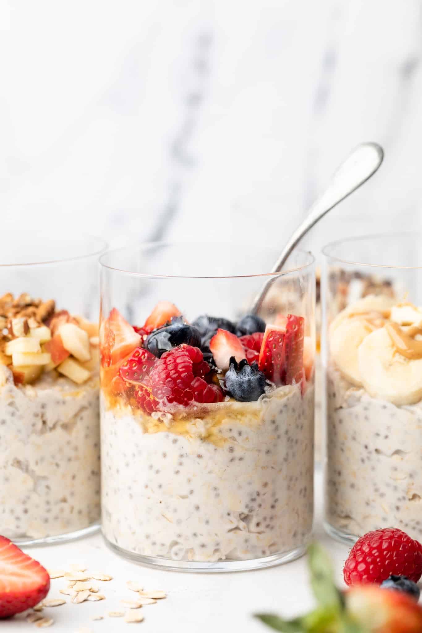 A jar with overnight oats made with coconut milk with berries and a spoon.