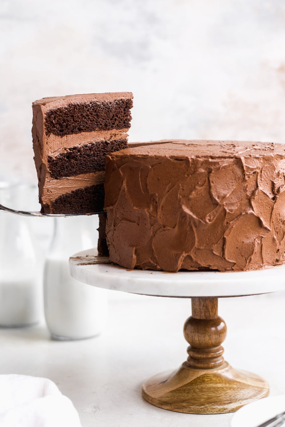 A slice of paleo chocolate cake being lifted from the cake stand.