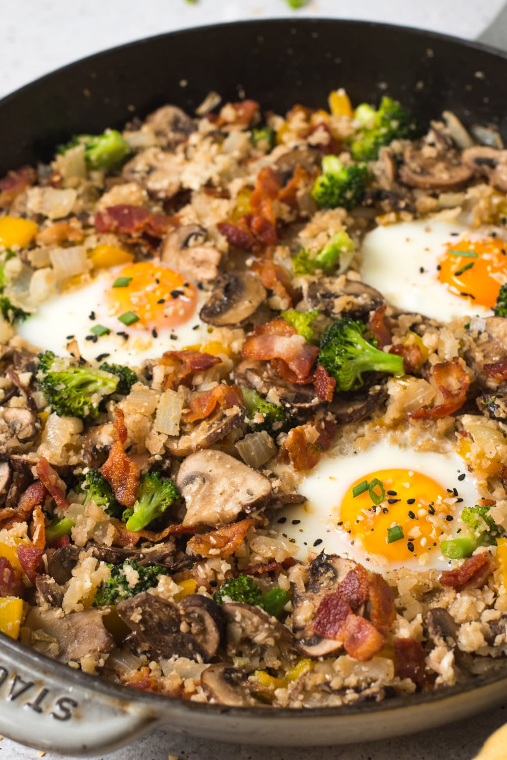 Close up of broccoli, eggs, cauliflower rice, and mushrooms in a pan. 