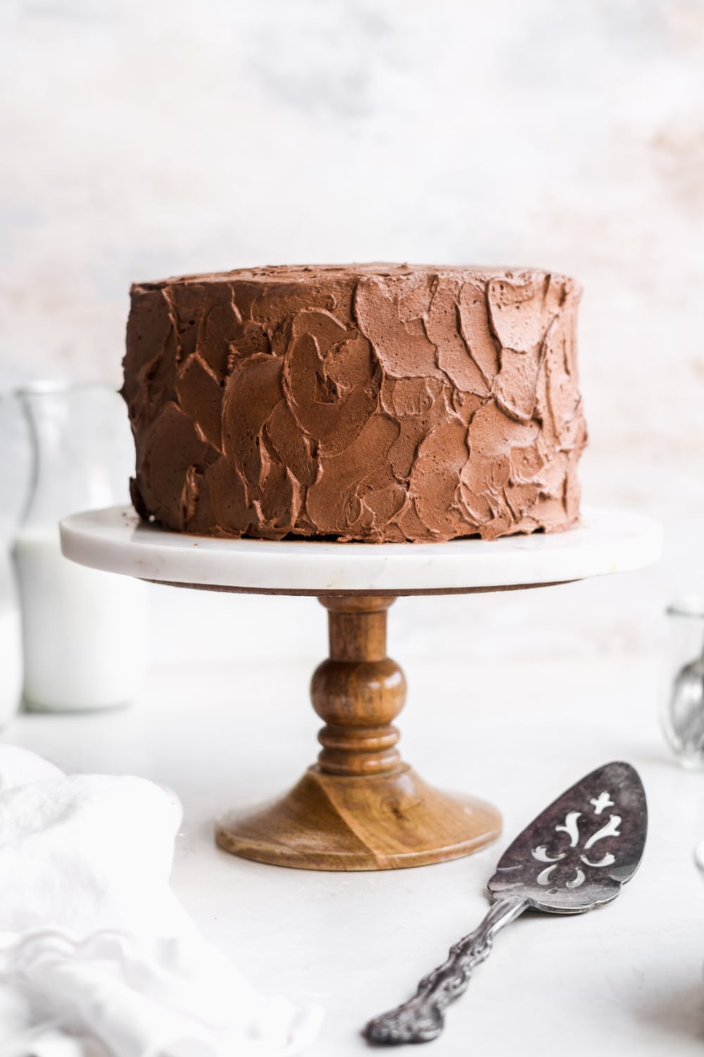paleo chocolate layer cake with frosting on a cake stand