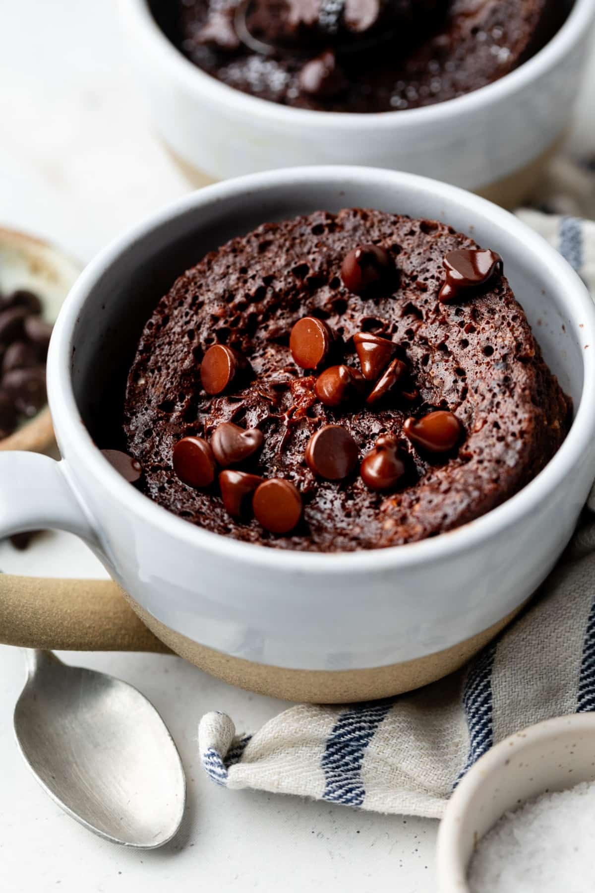 The cake completely baked in the mug with chocolate chips that are starting to melt on top.
