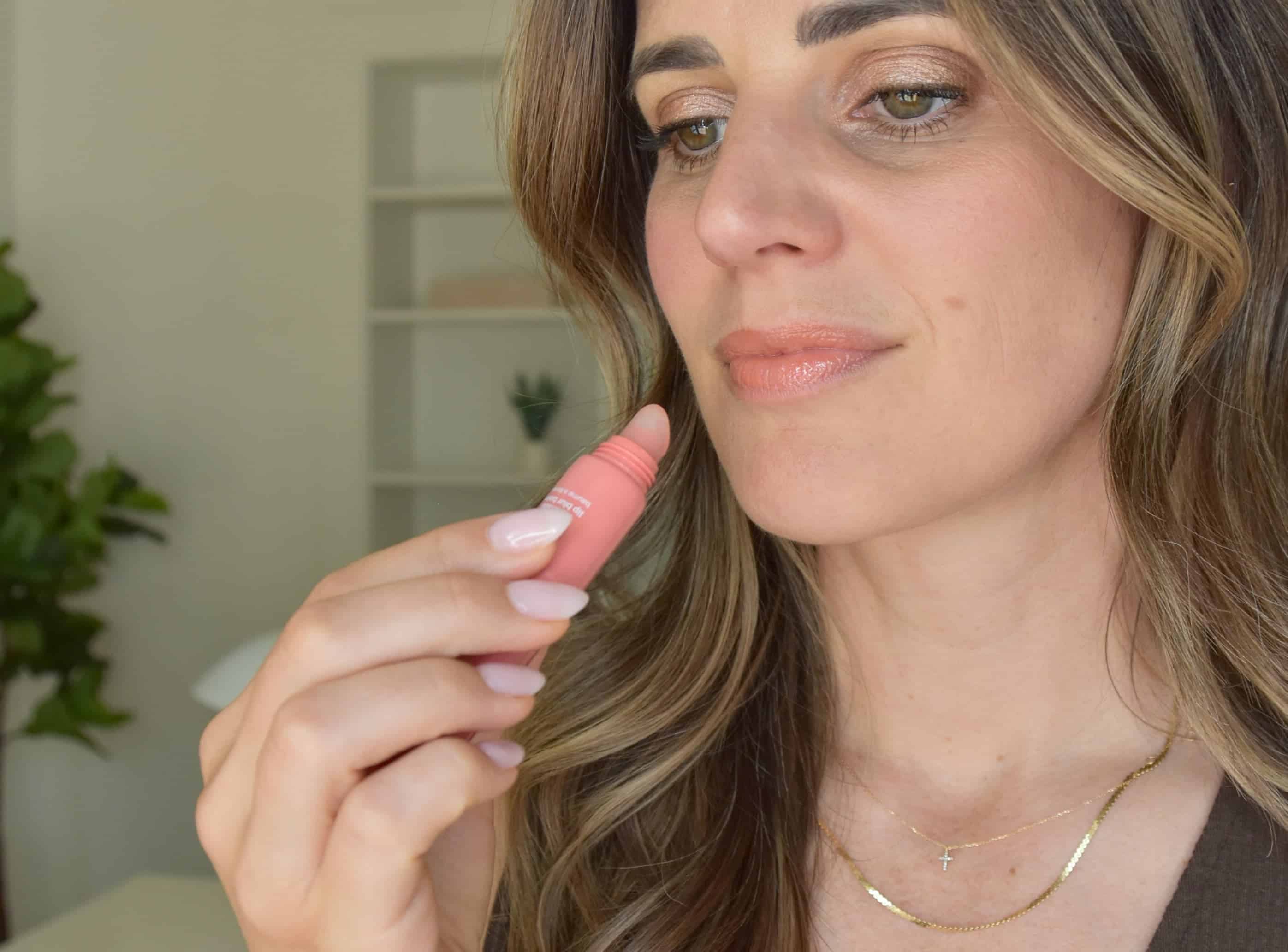 Applying the Cocokind Coral Pink lip balm to my lips to review the texture and color.