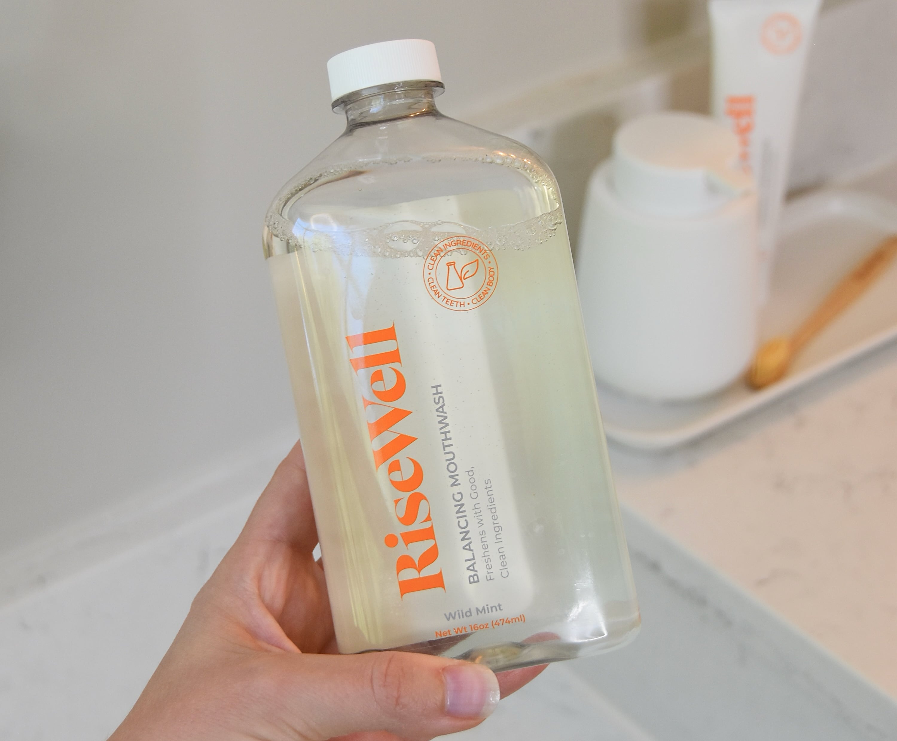 Holding the RiseWell Mouthwash for review over the bathroom counter.