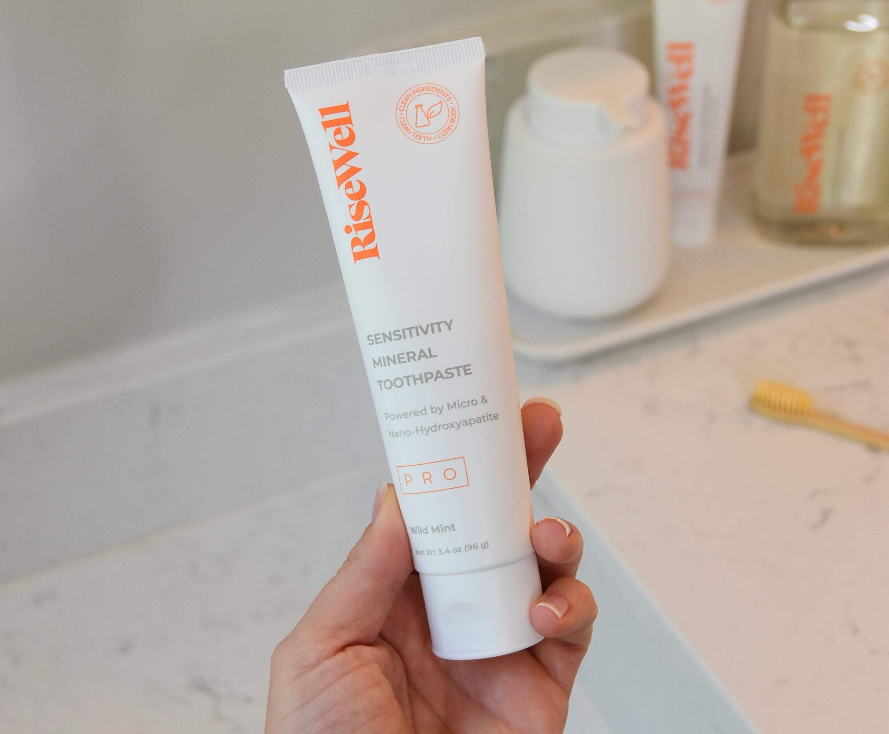 Holding the Pro toothpaste over the bathroom counter.