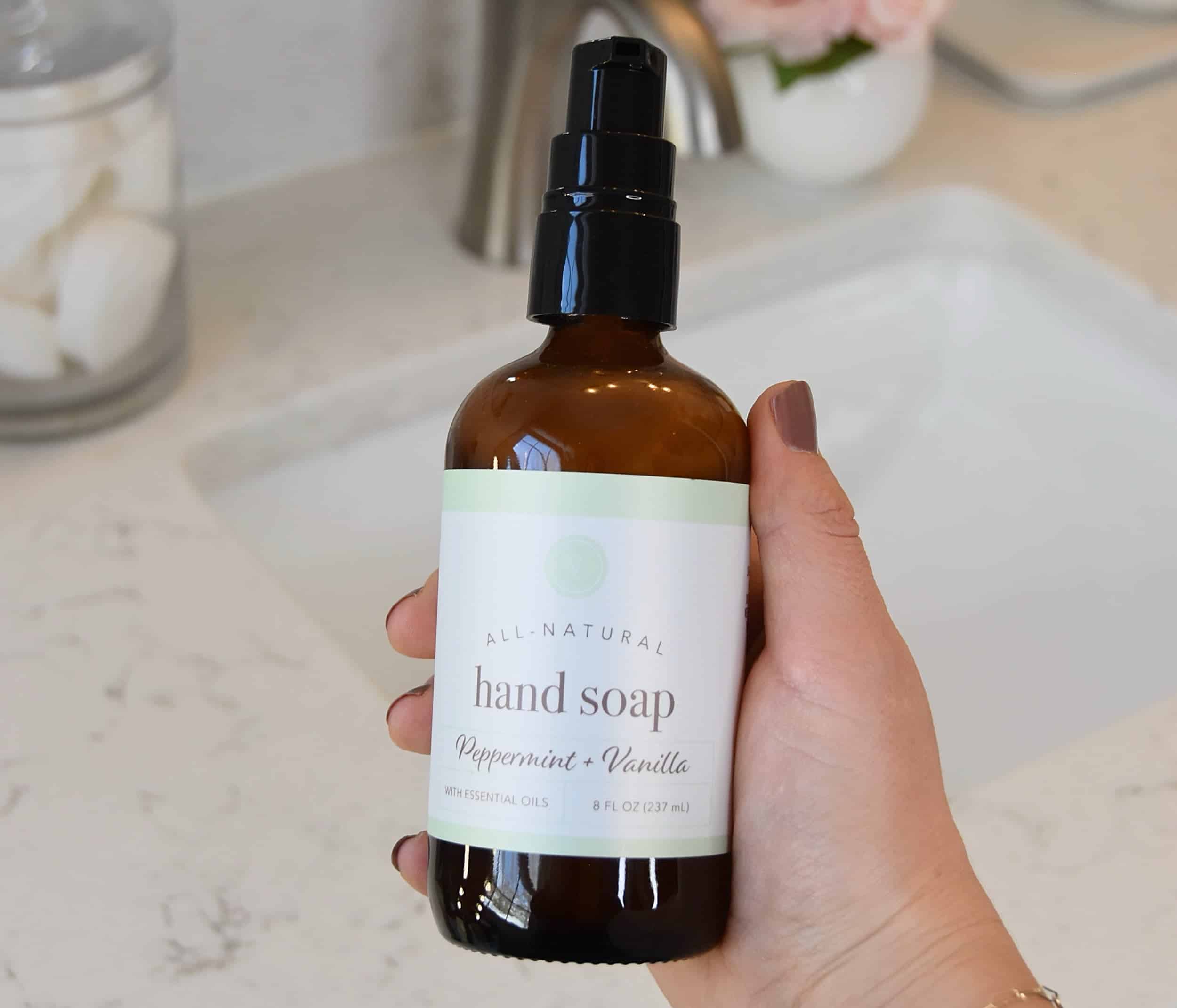 A bottle of the hand soap in front of the bathroom sink.