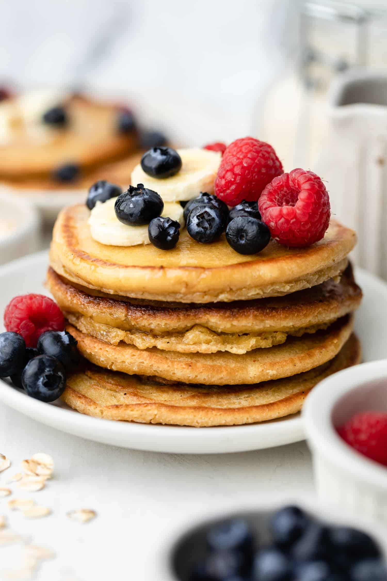 Stack of oat flour pancakes with berries on top.