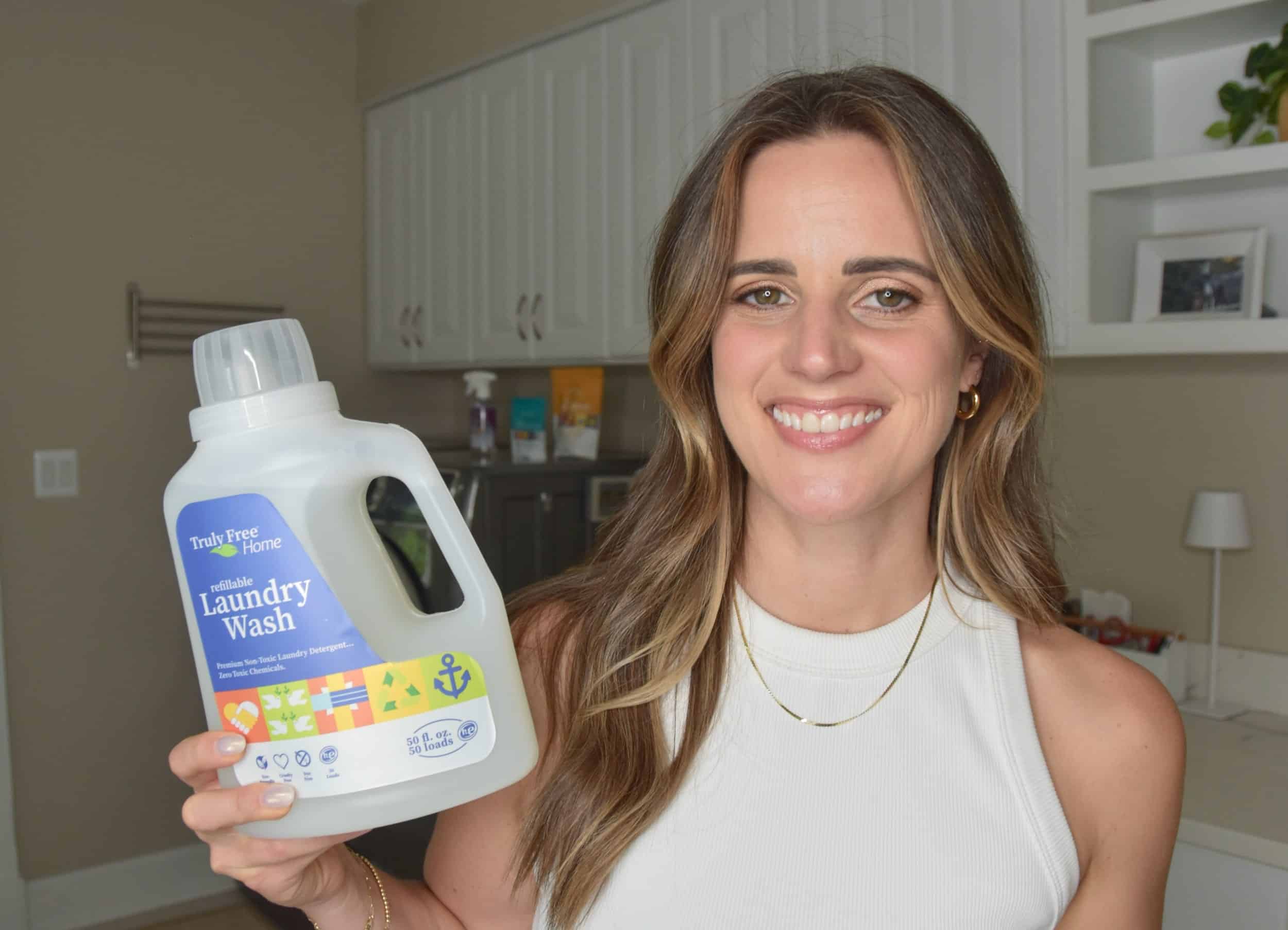 Noelle holding a bottle of laundry detergent in the laundry room.